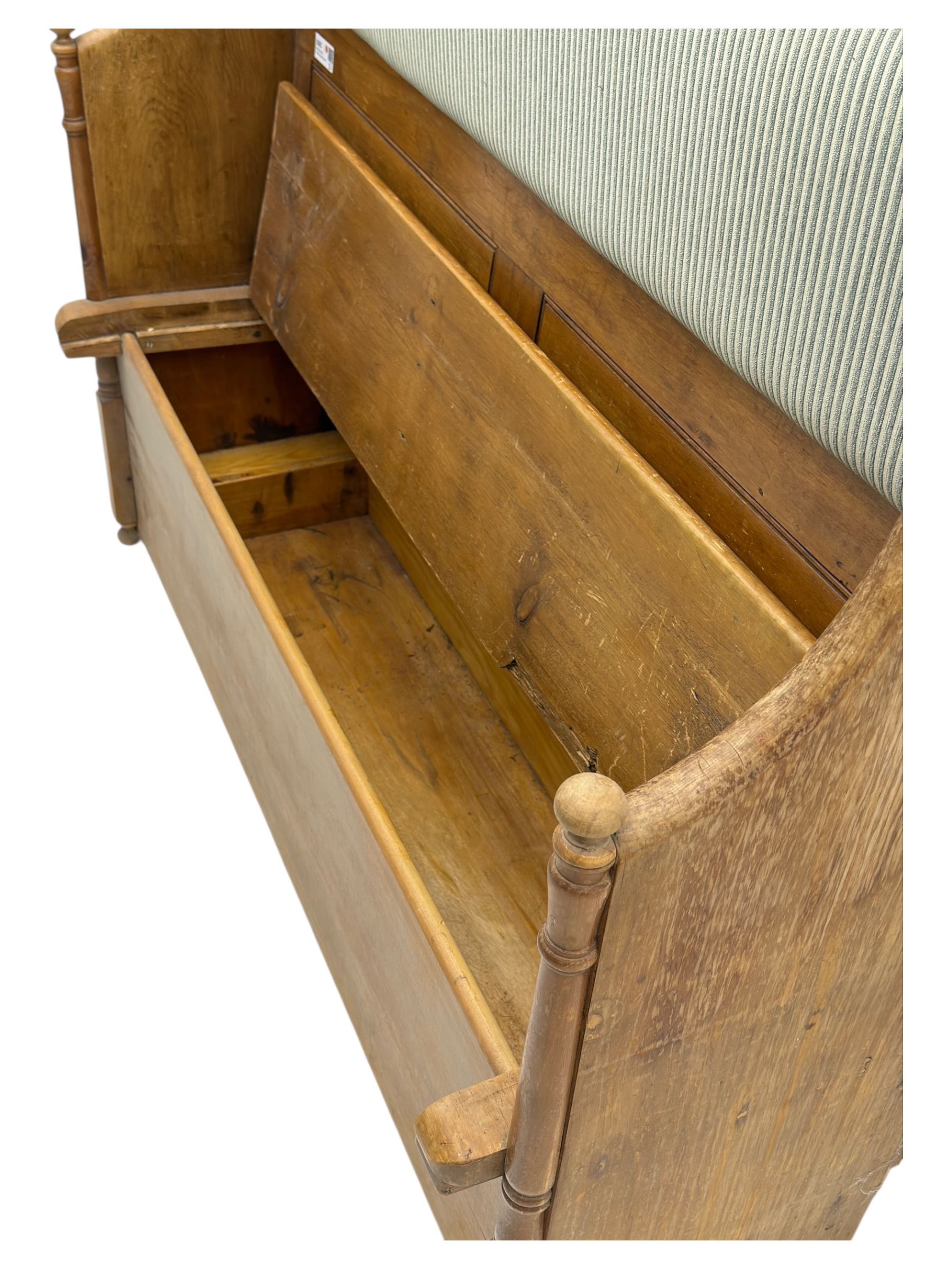 Early 20th century waxed pine pew, inset upholstered striped back panel with hinged box seat enclosing storage, shaped arms and turned supports