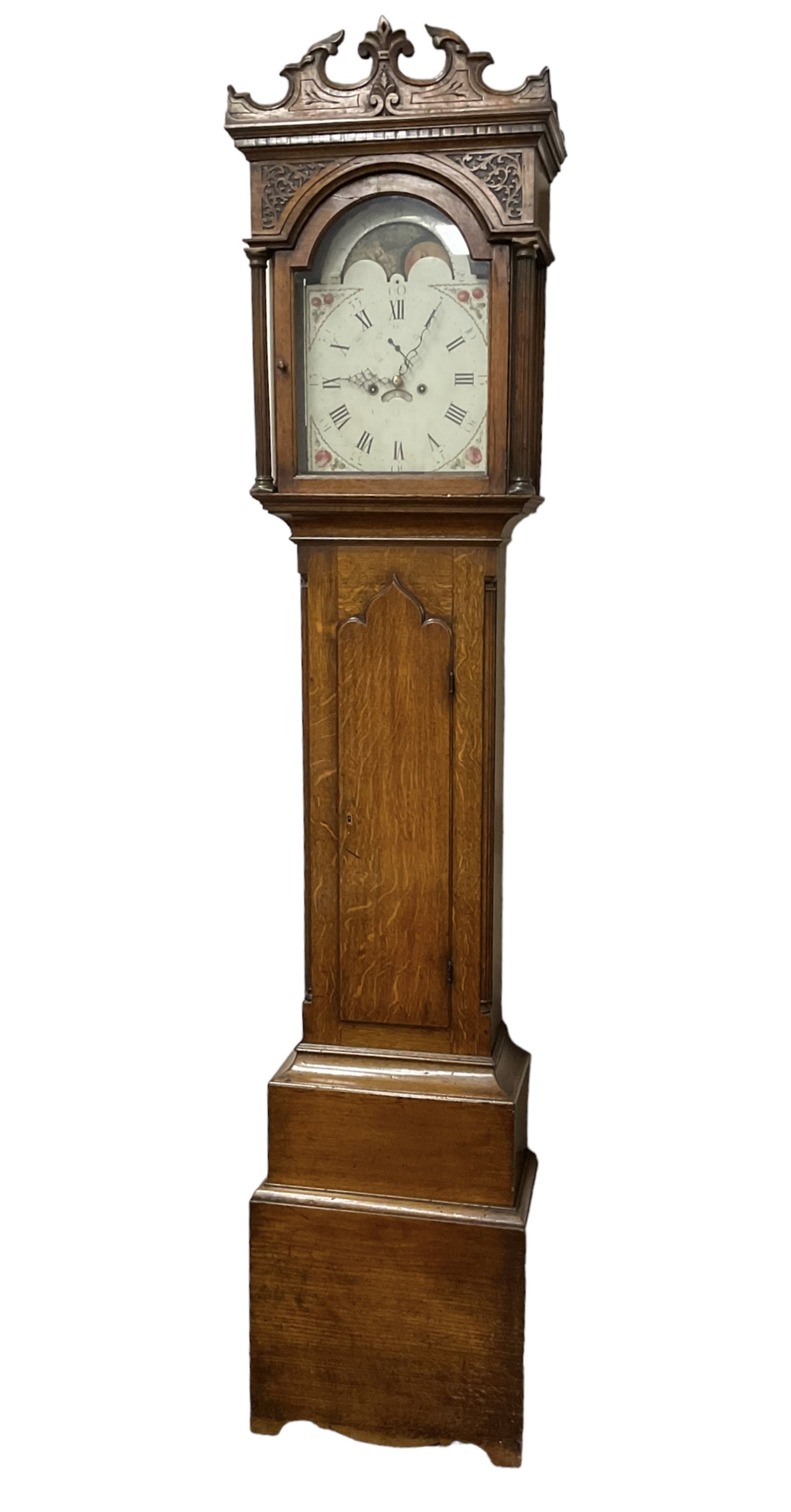 George Clapham of Brigg - Late 18th century 8-day oak cased longcase clock c1790 - flat topped hood with later carved addition, dog tooth moulding and blind fretwork beneath, break arch hood door flanked by reeded pilasters and capitals, trunk with canted corners and  door with a triple arched top, plinth with a later base with decoratively shaped feet, early painted dial with flowers enclosed in a gesso border to the spandrels, rolling moon to the arch, seconds dial and calendar aperture, Roman numerals and five minute Arabic's with makers name (indistinct), dial pinned via a false plate to a rack striking movement. With weights, key and pendulum.