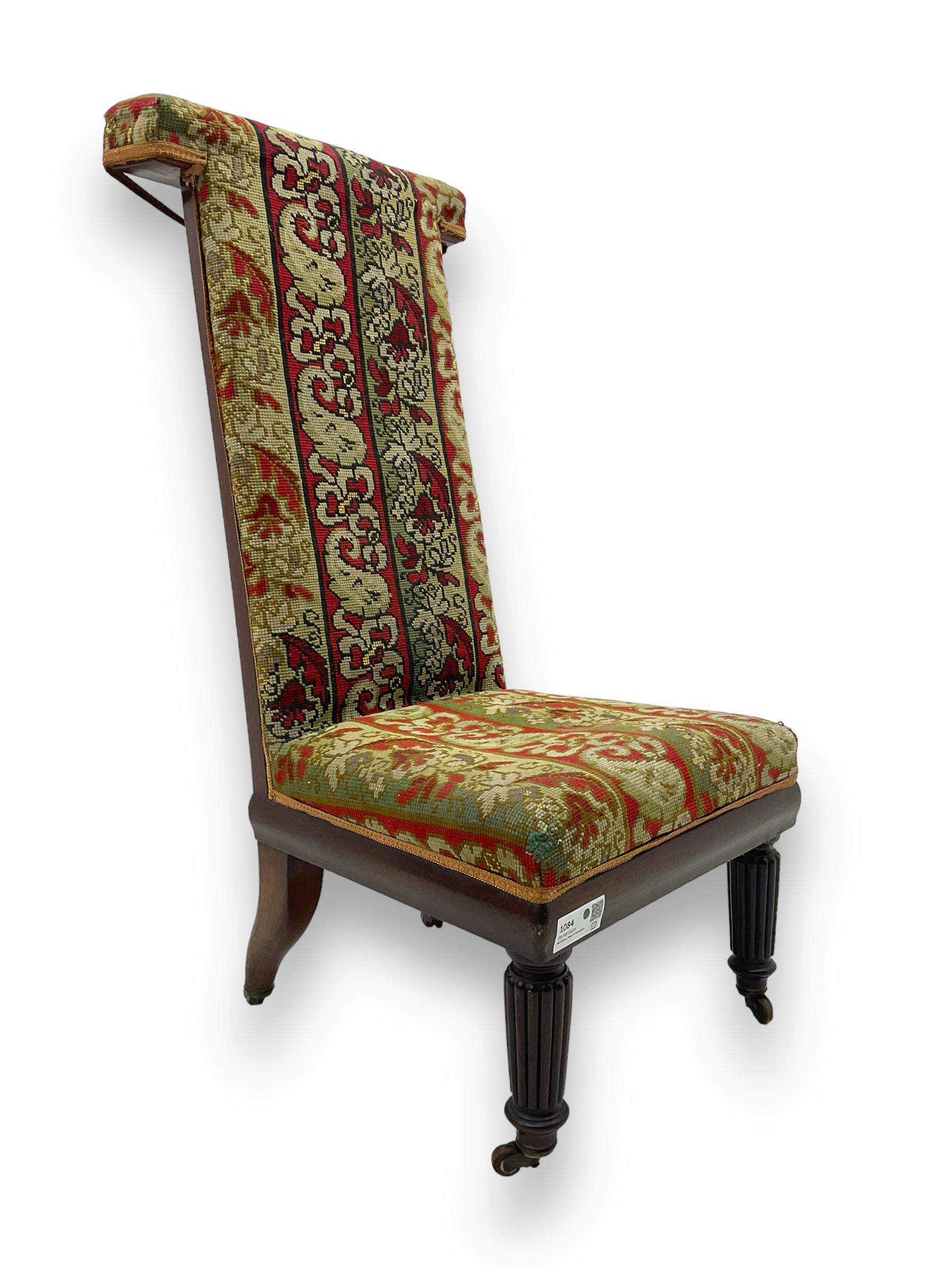 19th century mahogany framed prie-dieu chair, upholstered in red and green patterned fabric, high back with rolled top, standing on turned front supports with castors
