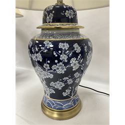 Pair of blue and white table lamps, each of baluster form, decorated with prunus blossom, within stylised borders, raised upon circular gilt base, excluding fittings H48cm