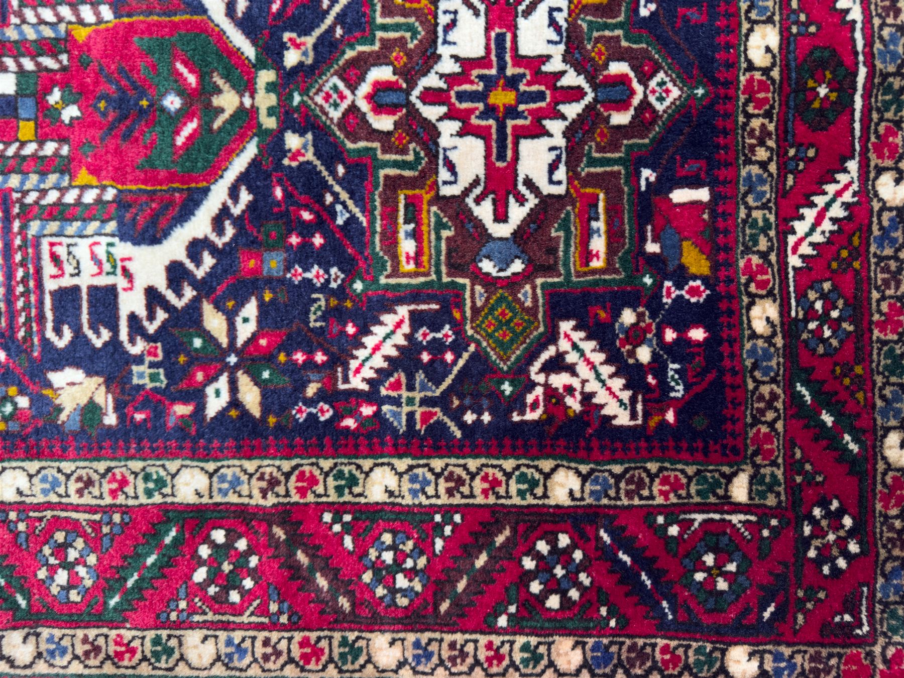 Northwestern Persian Heriz hand-knotted runner, dark indigo field with a series of linked stepped medallions in madder red, ivory, and green, flanked by angular floral motifs, within a madder red border of stylized rosettes and geometric vine motifs 405cm x 95cm