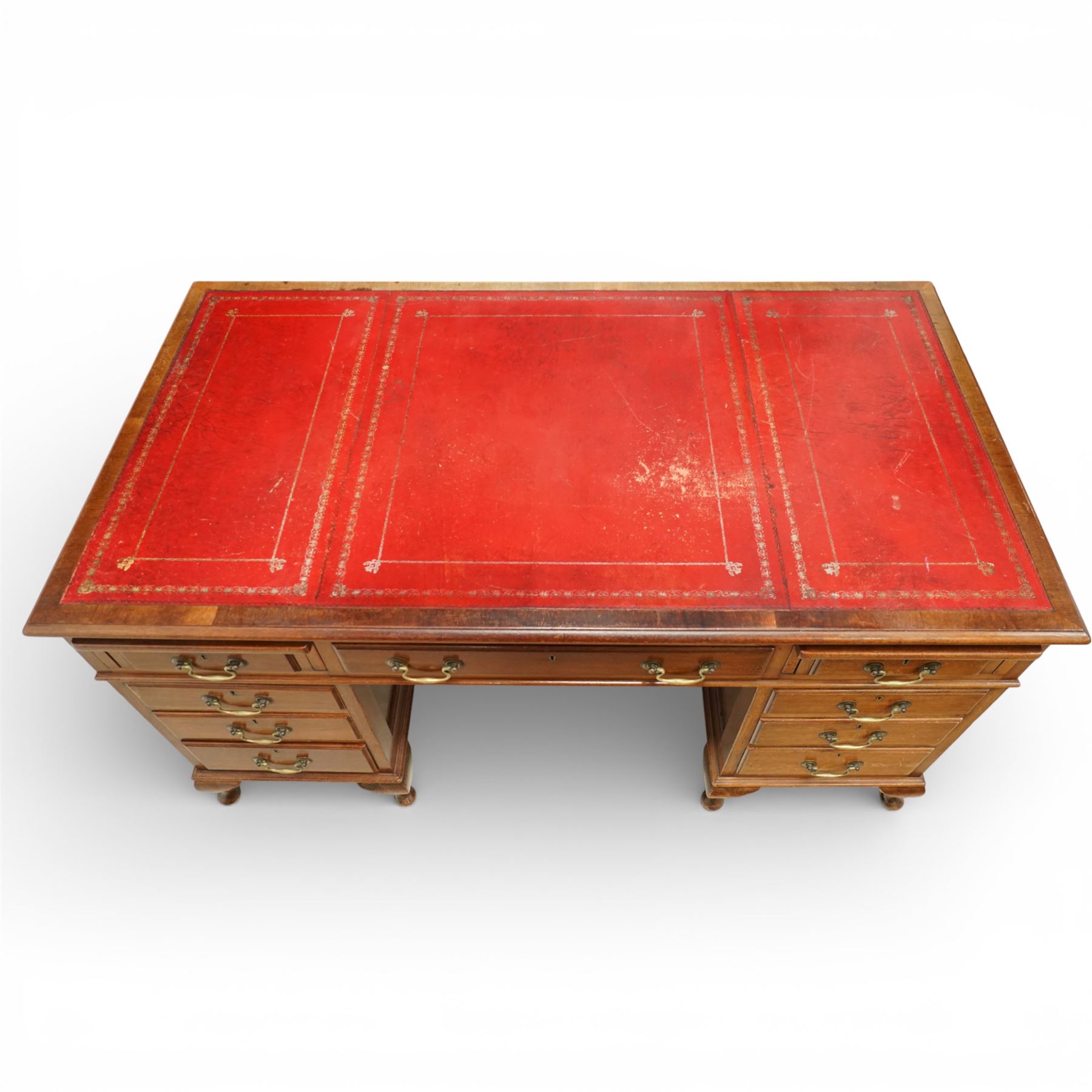 Late 19th century mahogany pedestal desk, rectangular top inset with worn red leather writing surface with gilt tooling, three frieze drawers above opposing pedestals each fitted with four graduated drawers, brass swan neck handles and escutcheons, panelled sides and back, raised on turned feet