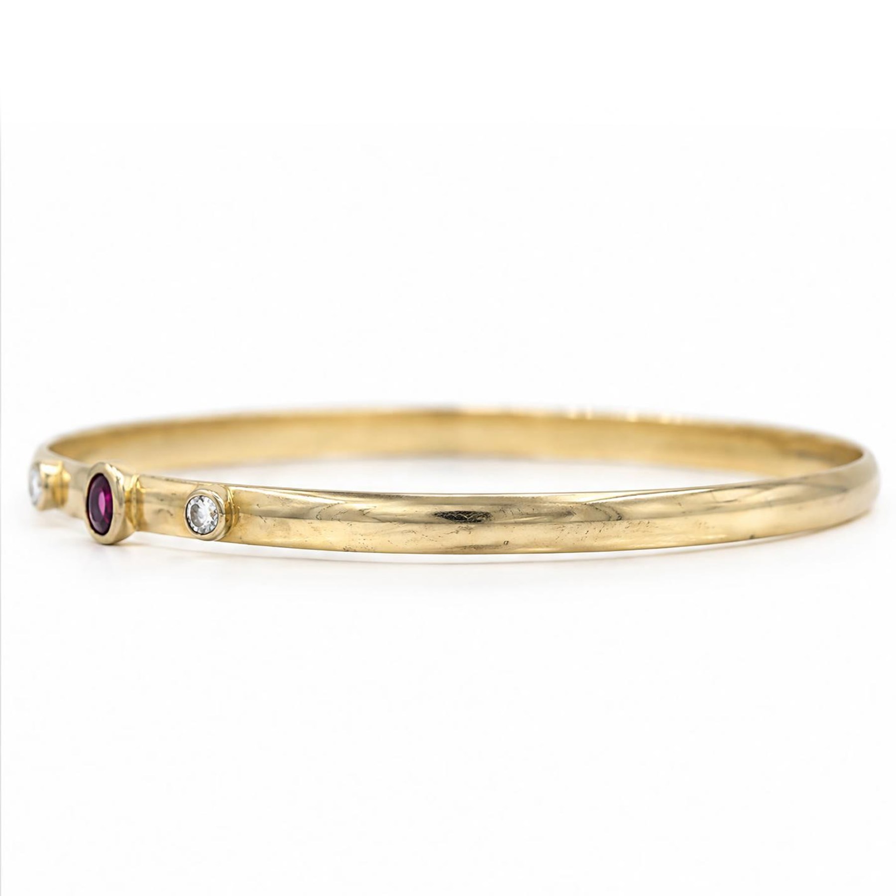 18ct gold ruby and diamond bangle, single oval cut ruby set between two round brilliant cut diamonds, stamped 750