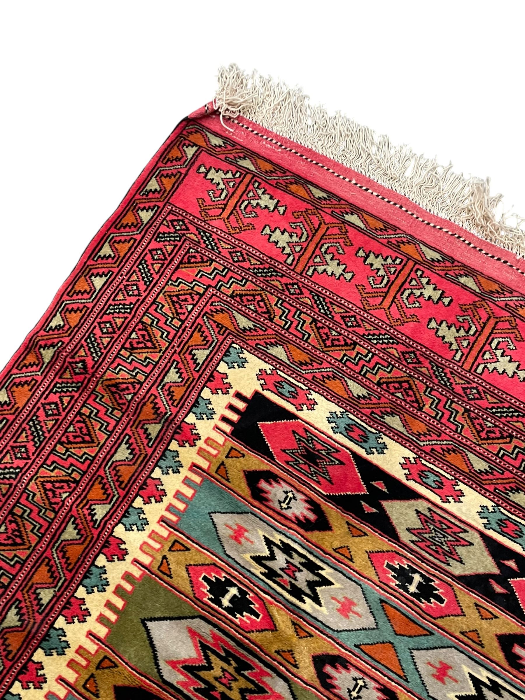 Turkaman red ground rug, the field divided into horizontal rows and decorated with geometric motifs, intricately pattern borders and end panels