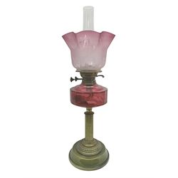 Victorian oil lamp, with brass corinthian column, cranberry glass reservoir and stepped ceramic base, H66cm