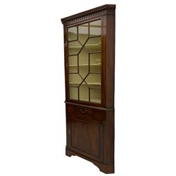 George III mahogany floor standing corner display cabinet, dentil cornice, upper astragal glazed door above small drawer and lower cupboard, on bracket feet, in two sections
