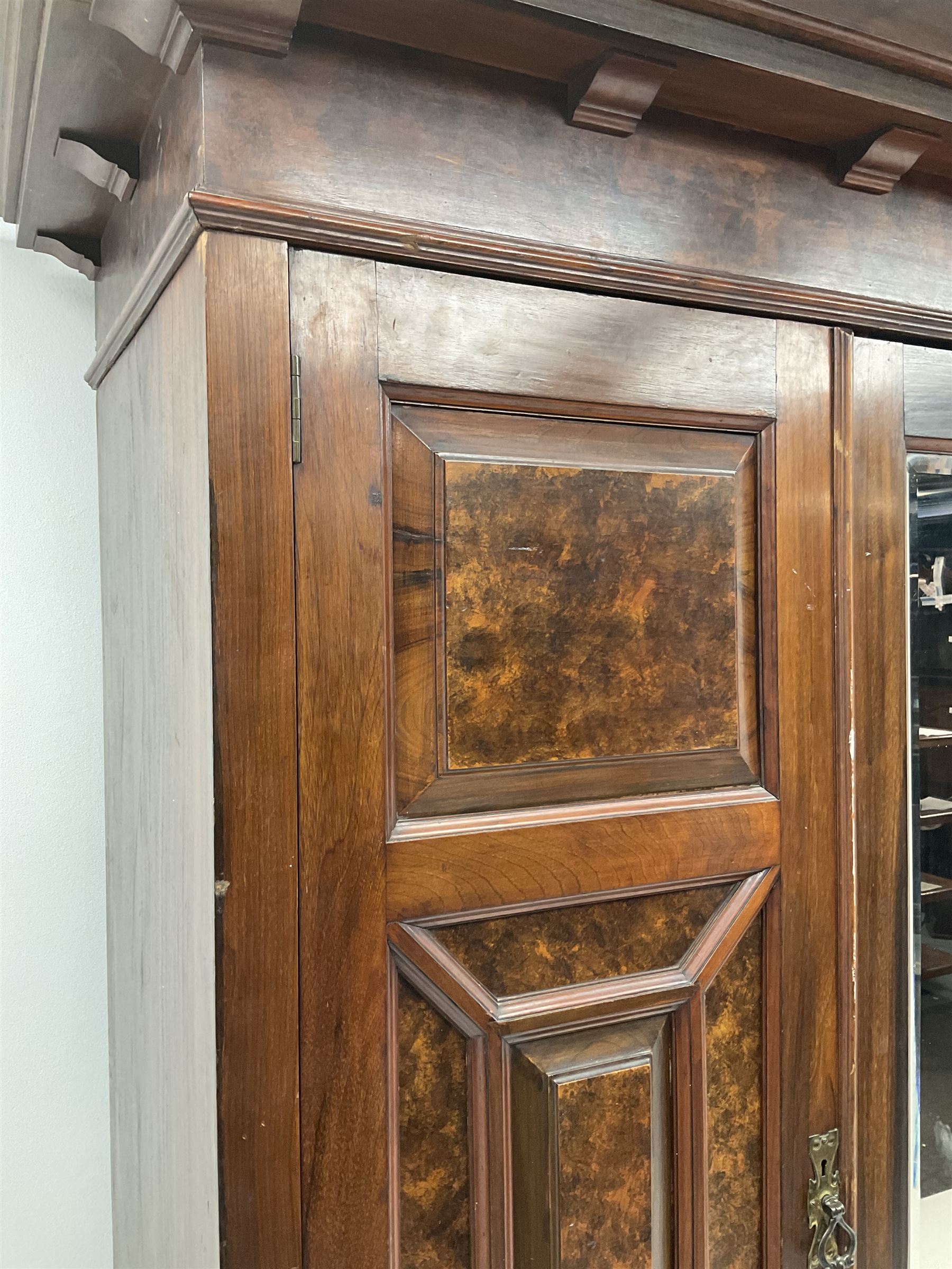 Large late Victorian walnut wardrobe, projecting cornice of central bevelled mirror and two panelled doors, two drawers to base