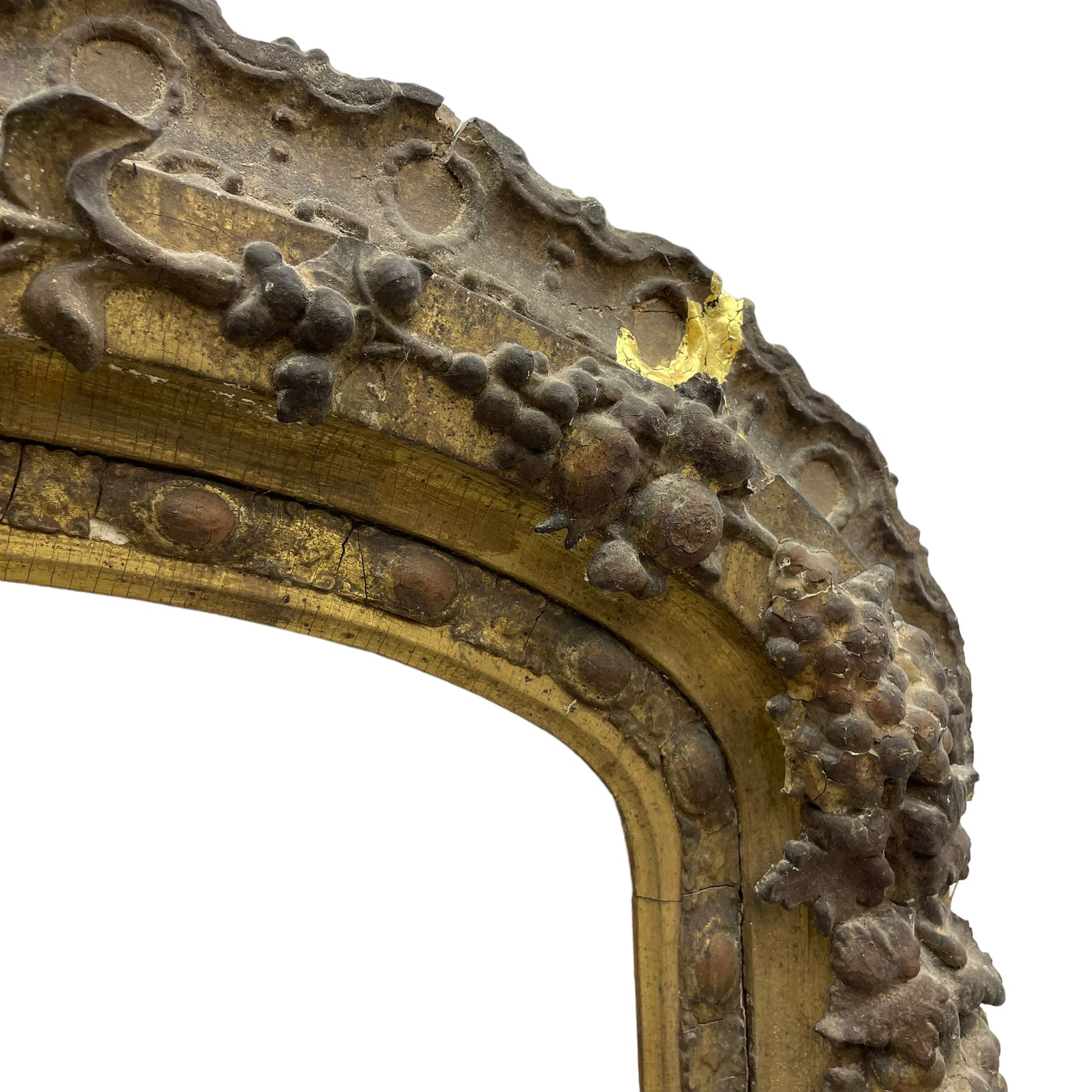 19th century giltwood and gesso moulded picture or mirror frame, the arched cresting rail mounted by central cartouche decorated with foliate scrolls and fruit, the outer frame decorated with scalloped edge and shell mouldings, trailing foliage with flower head and fruit to the central band, egg and dart moulded inner slip