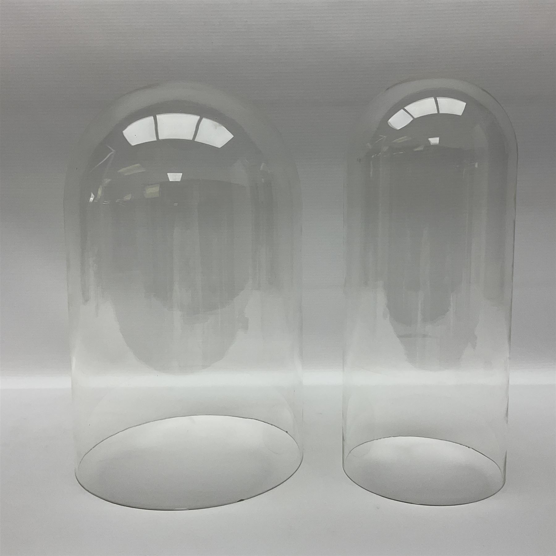 Tabletop glass display cabinet, with hinged door, together with two glass domes