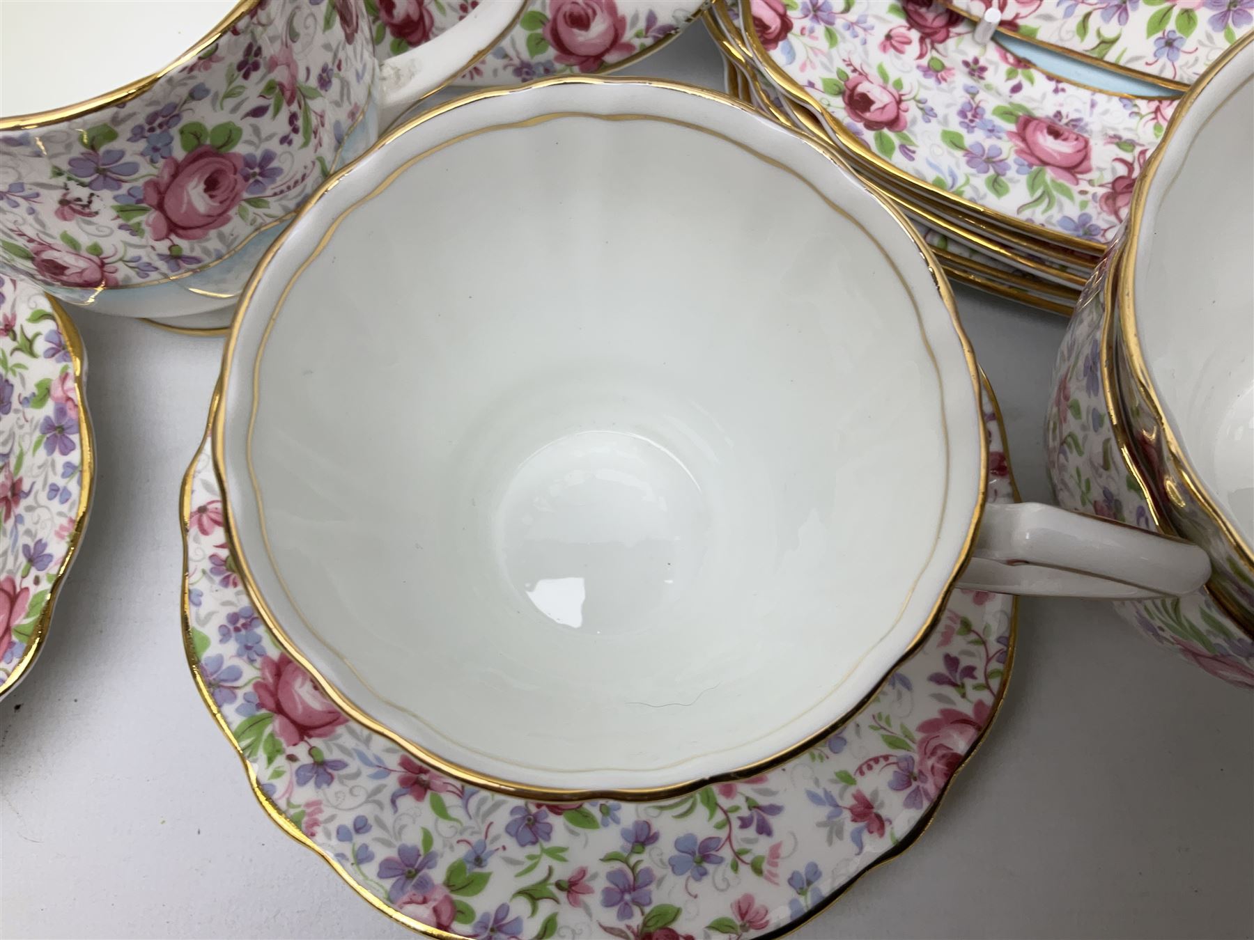 Windsor tea service for six decorated with blooming pink roses and purple flowers amongst foliage