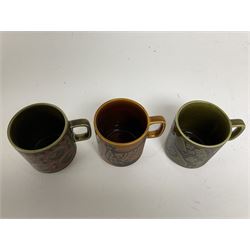 Three Hornsea pottery mugs, one decorated with fish on a green ground, the second chickens on a brown grounds and the third pigs on a green ground (3)