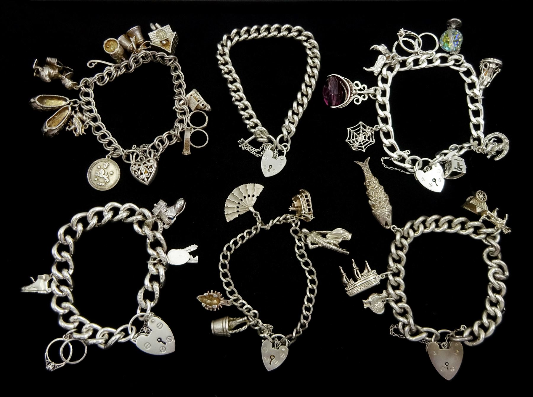 Six silver charm bracelets, charms including cuckoo clock, Donald duck, spiders web, keys, hedgehog and matador