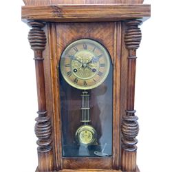 German early 20th century wall clock in a mahogany case with an architectural pediment and turned finial, with applied carving and pendant finials, fully glazed door with a visible gridiron pendulum, eight-day spring driven striking movement striking the hours on a gong, dial with Roman numerals to the chapter and a gilt repoussé centre.   

