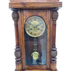 German early 20th century wall clock in a mahogany case with an architectural pediment and turned finial, with applied carving and pendant finials, fully glazed door with a visible gridiron pendulum, eight-day spring driven striking movement striking the hours on a gong, dial with Roman numerals to the chapter and a gilt repoussé centre.   

