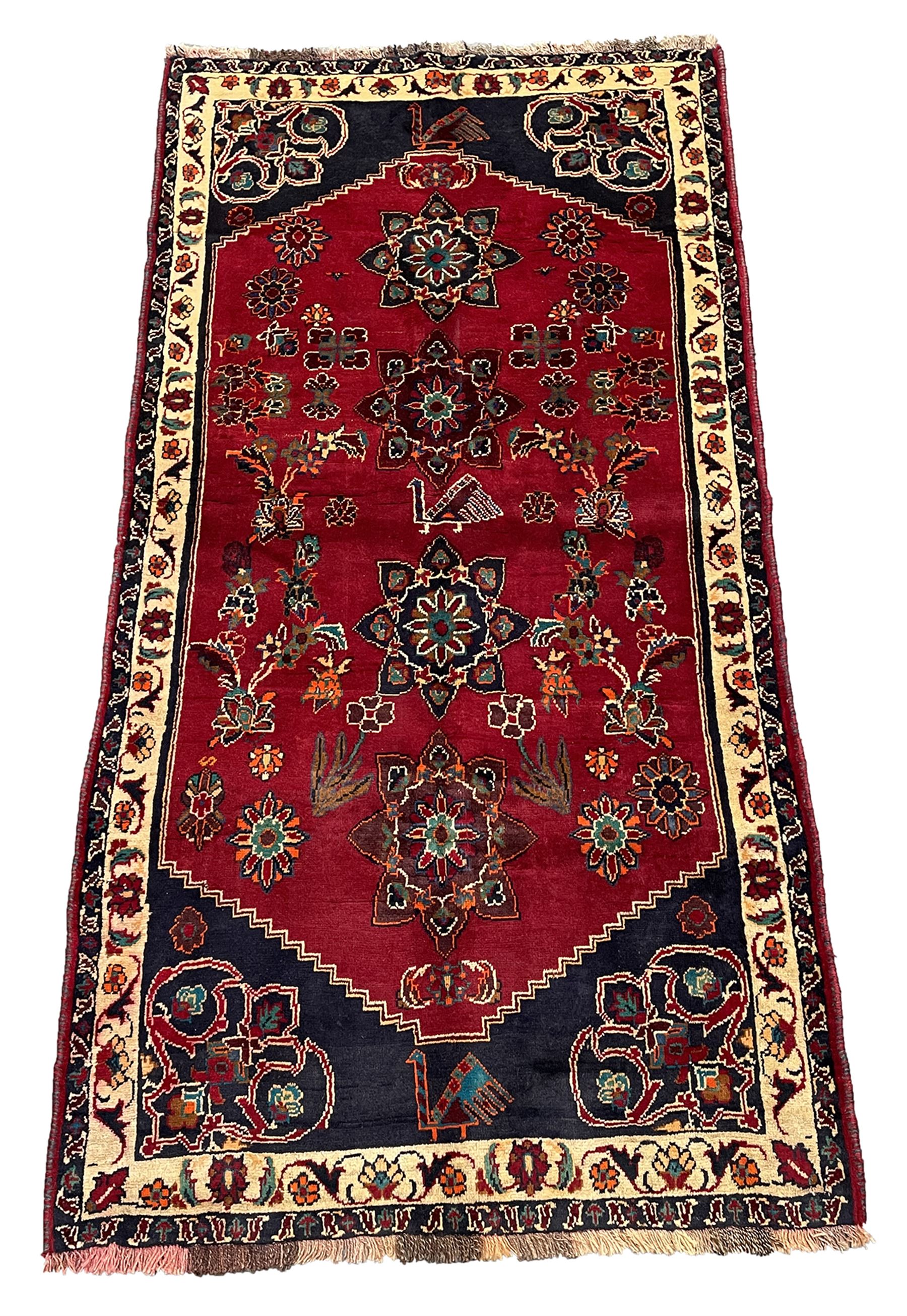 Persian rug, red ground field decorated with stylised flower heads and bird motifs, floral scrolling border