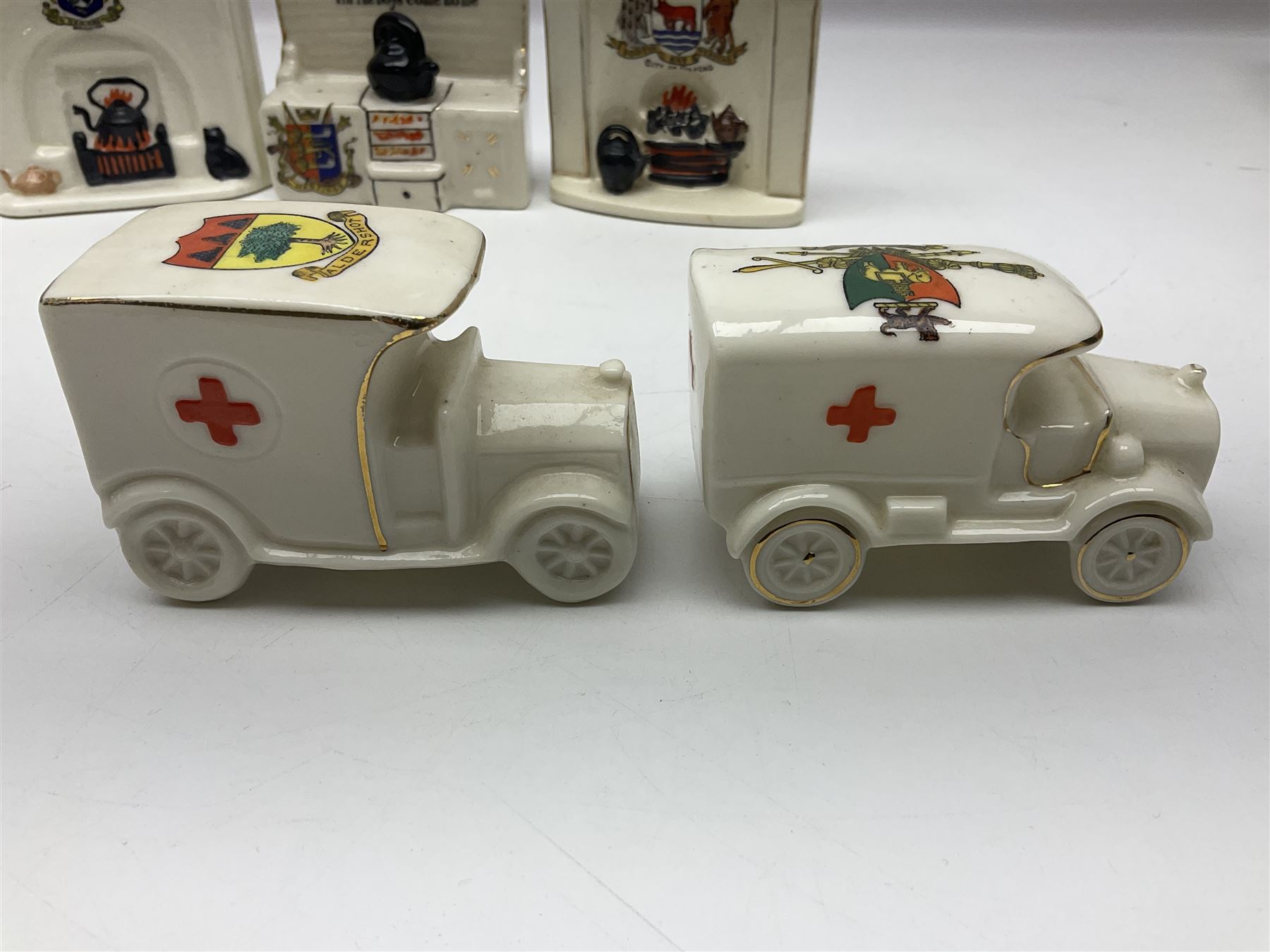 Ten WW1 crested china military models comprising seven field ambulances and three 'Home Fires Burning' fire-surrounds/range; various makers including Willow Art, Arcadian China, Grafton China, Savoy China, Carlton China etc; various crests including Devon, Aldershot, Portsmouth, West Ham, Coventry, Oxford, Hastings, Brighton etc (10)