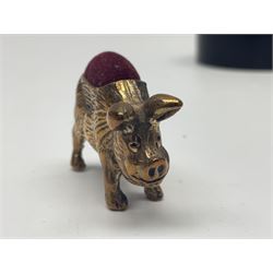 Three pin cushions, comprising gilt metal pig, silver plate shoe, circular pin cushion on threel feet, together with black pin holder with silver writing to the lid 