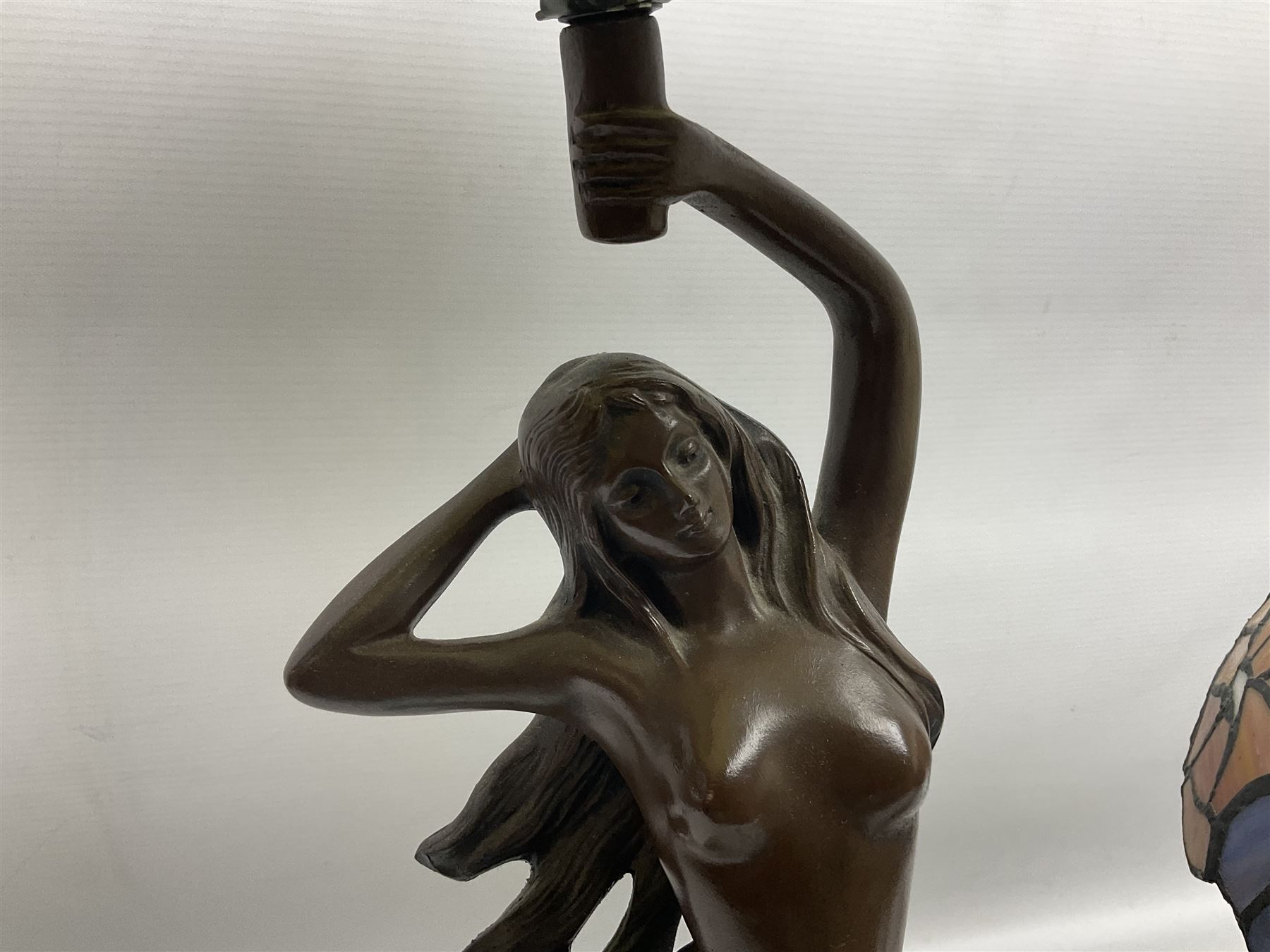 Tiffany style lamp in the form of a semi nude woman holding up a leaded lampshade together with a similar table lamp