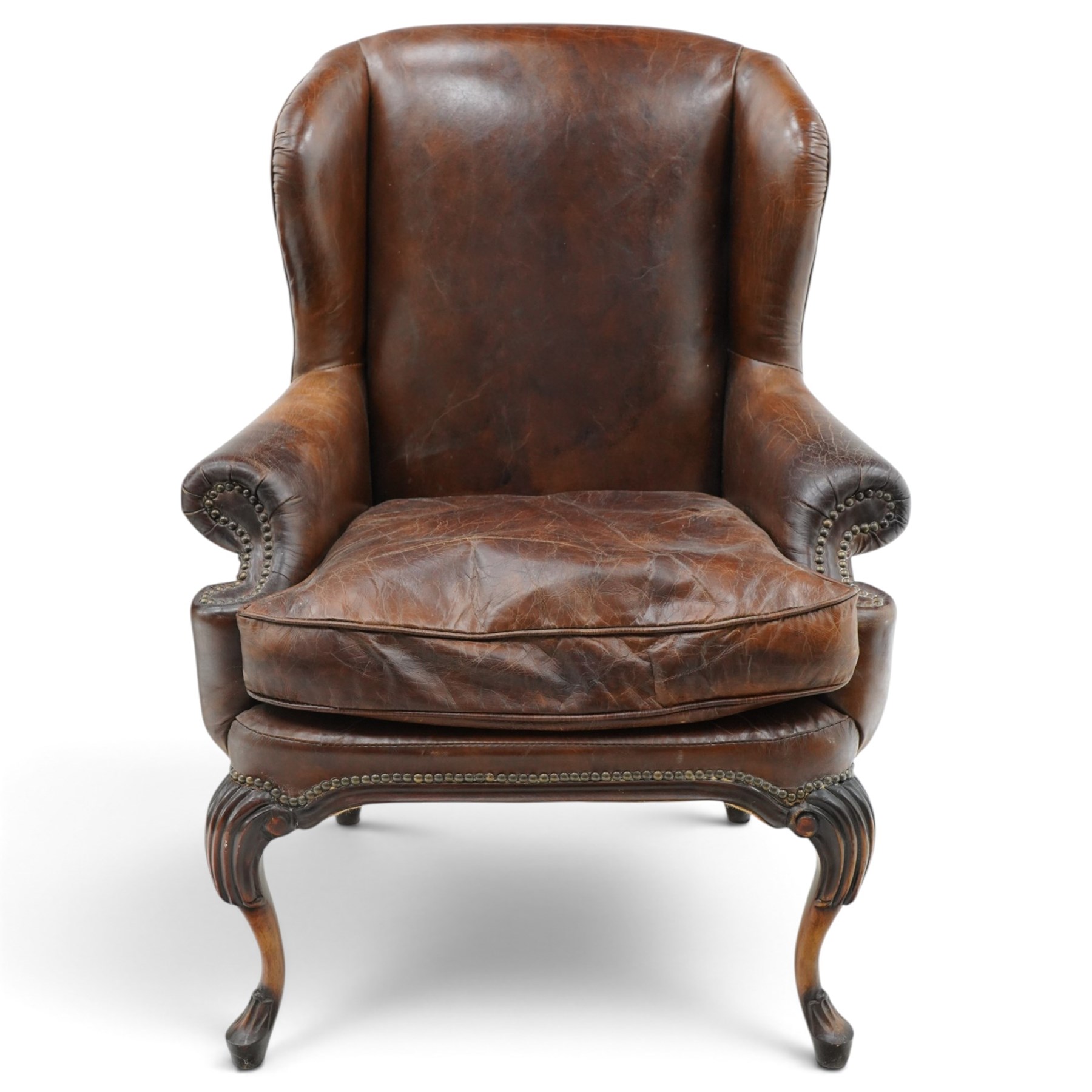 Pair of quality Queen Anne design mahogany framed wingback armchairs with matching footstools, the high sprung winged backs over rolled arms with studwork, raised on elegant reeded scroll carved cabriole supports, upholstered in deep chocolate brown leather (W82cm D75cm H112cm), the footstools with ovoid padded seat over studwork and moulded lower rail and cabriole supports (W65cm D42cm H48cm)