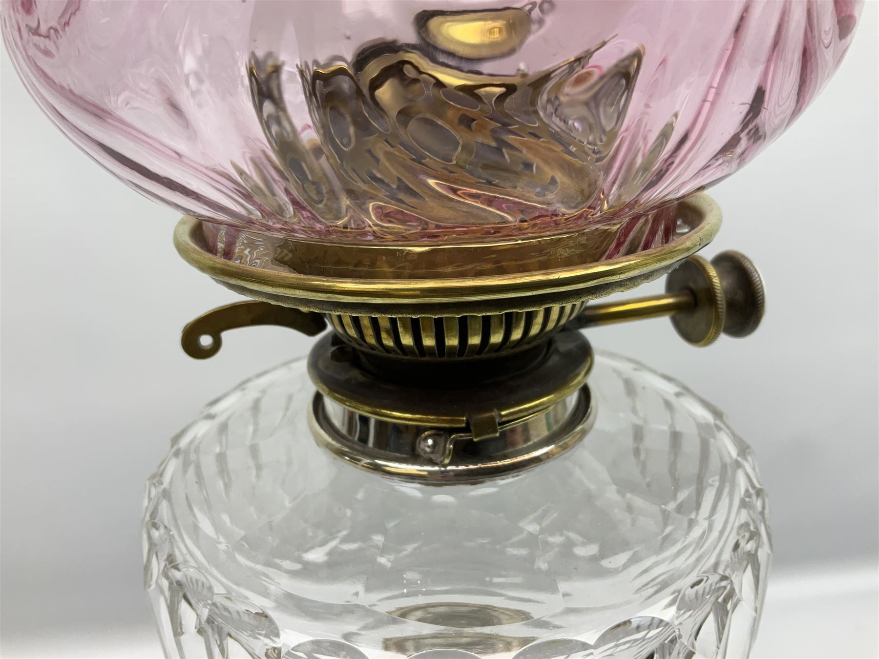 20th century Hawksworth, Eyre & Co silver plated oil lamp, the octagonal stepped base with engraved dedication, leading to an octagonal column supporting a faceted clear glass reservoir, Hinks Duplex burner, clear glass chimney, and cranberry glass shade, overall H71.5cm