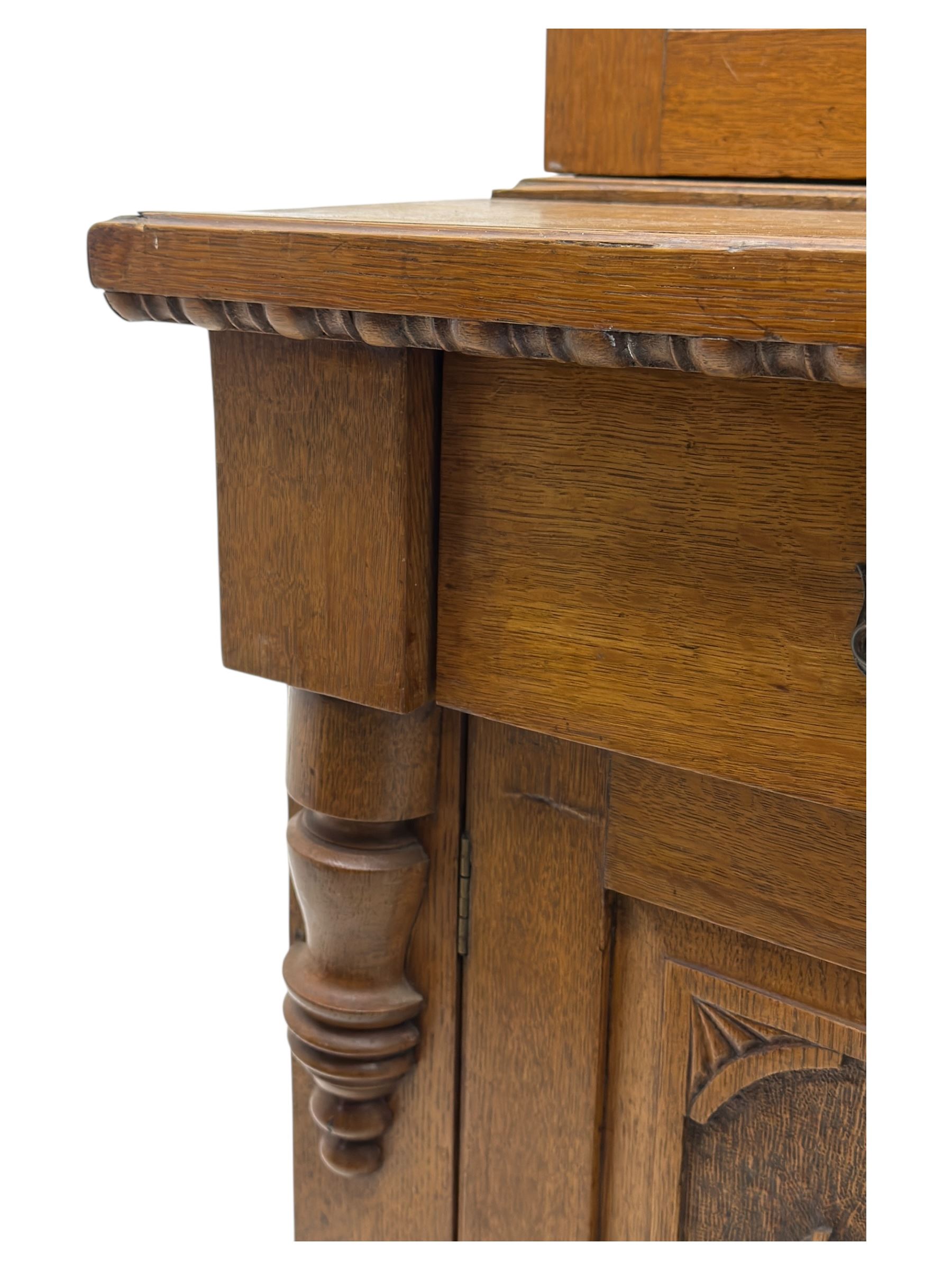 Late 19th century pine dresser, the projecting cornice with dentil and spindle moulded frieze above a three-tier plate shelves, flanked by glazed doors, the base fitted with three frieze drawers over arched apron and carved floral panelled cupboard doors, raised on turned feet