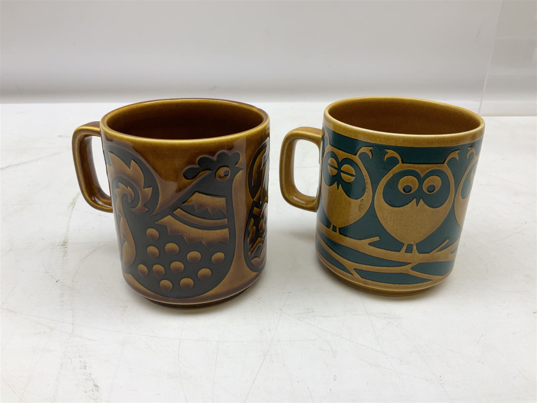 Collection of 1970s Hornsea mugs designed by John Clappison, comprising six Train Robber pattern examples together with owl patterned example on dark teal ground, and further example decorated with stylised hen and chick and egg, approx 9cm, together with four small cup bowls, all with stamped Hornsea marks beneath