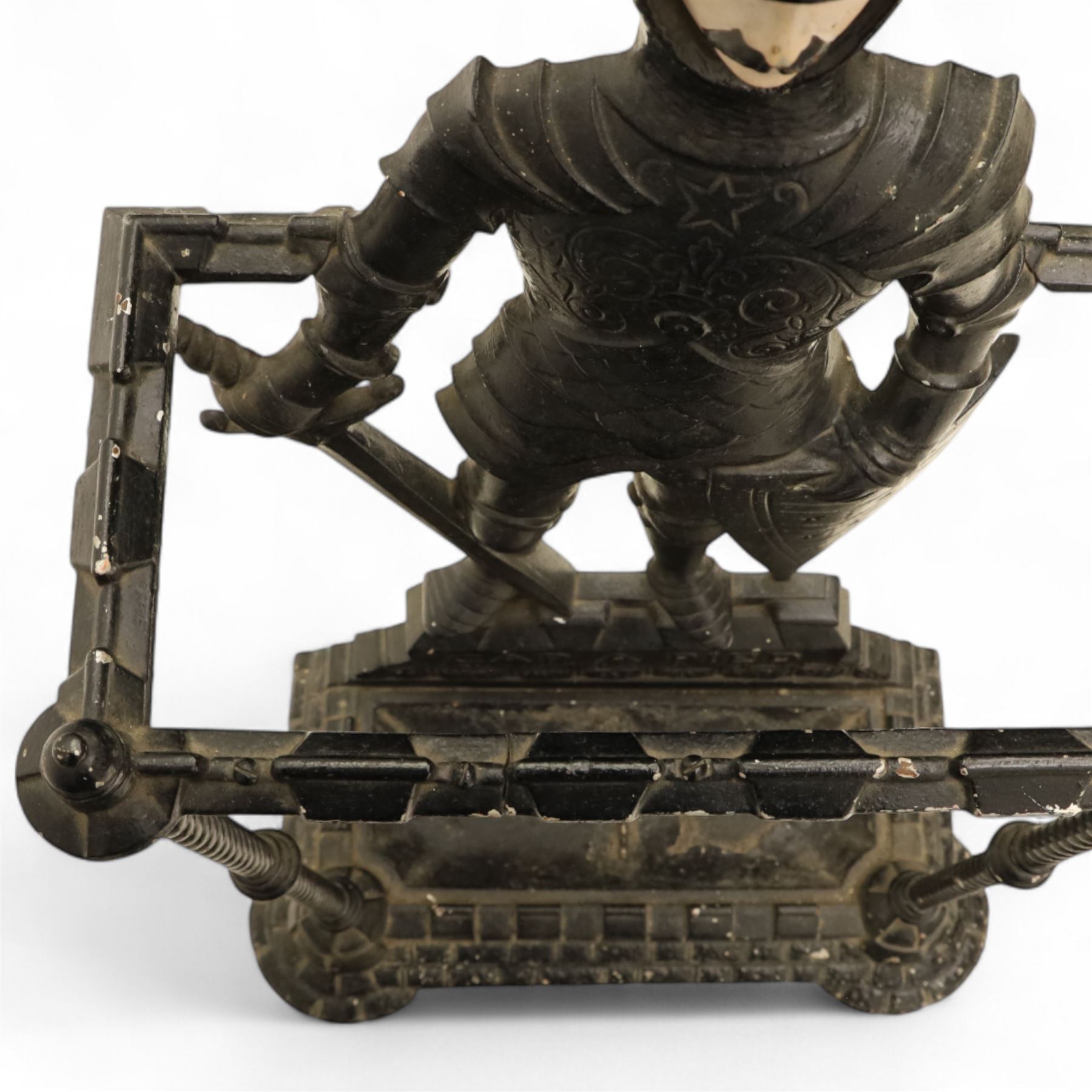 Early 20th century painted cast iron hall stand, formed as a standing armoured figure with red and yellow feathered crest, twin rails and integral drip tray with castellated edge