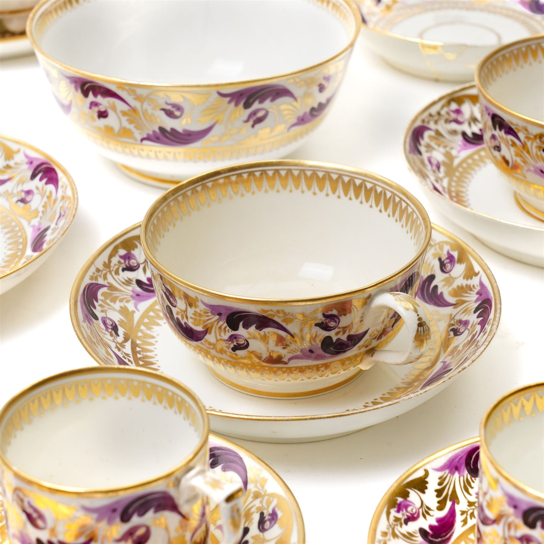 Early 19th century Derby tea and coffee service painted with a border pattern of purple and gilt leaves and flowers comprising four large cups with five saucers, nine coffee cans with twelve saucers, tea pot and stand, slop bowl, milk jug and two plates, red painted mark.