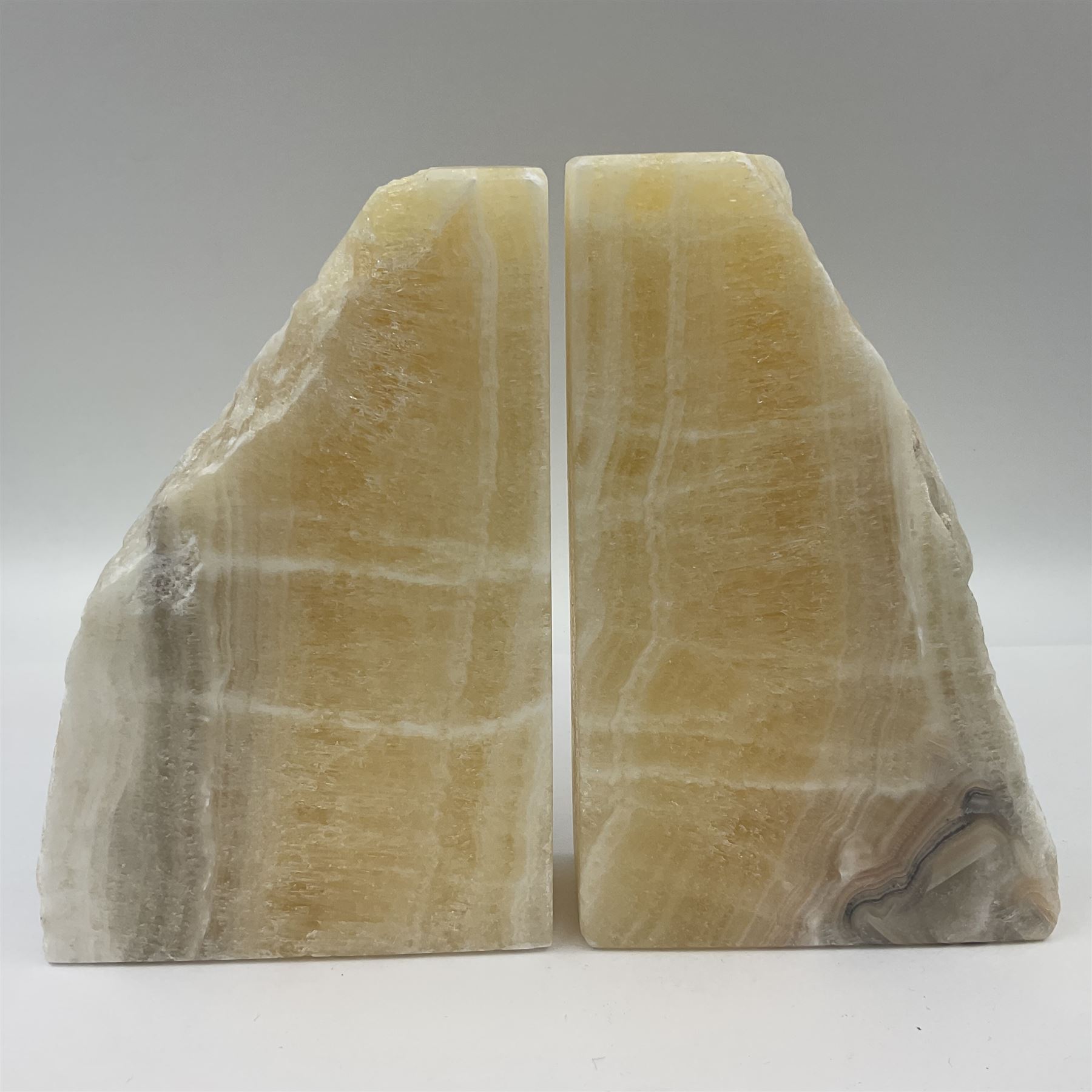 Pair of honey onyx bookends of rectangular form with polished to three sides with a raw outer edge, H18cm 
