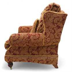 Duresta – pair of armchairs, upholstered in red and gold damask fabric with piped edges, scroll arms and loose feather-filled cushions, raised on turned wooden feet with brass castors