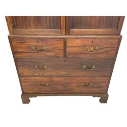 George III mahogany Gentleman's linen press, the projecting cornice over two panelled cupboard doors enclosing three sliding trays, the base fitted with two short over three long graduating cock-beaded drawers, lower moulded edge over bracket feet