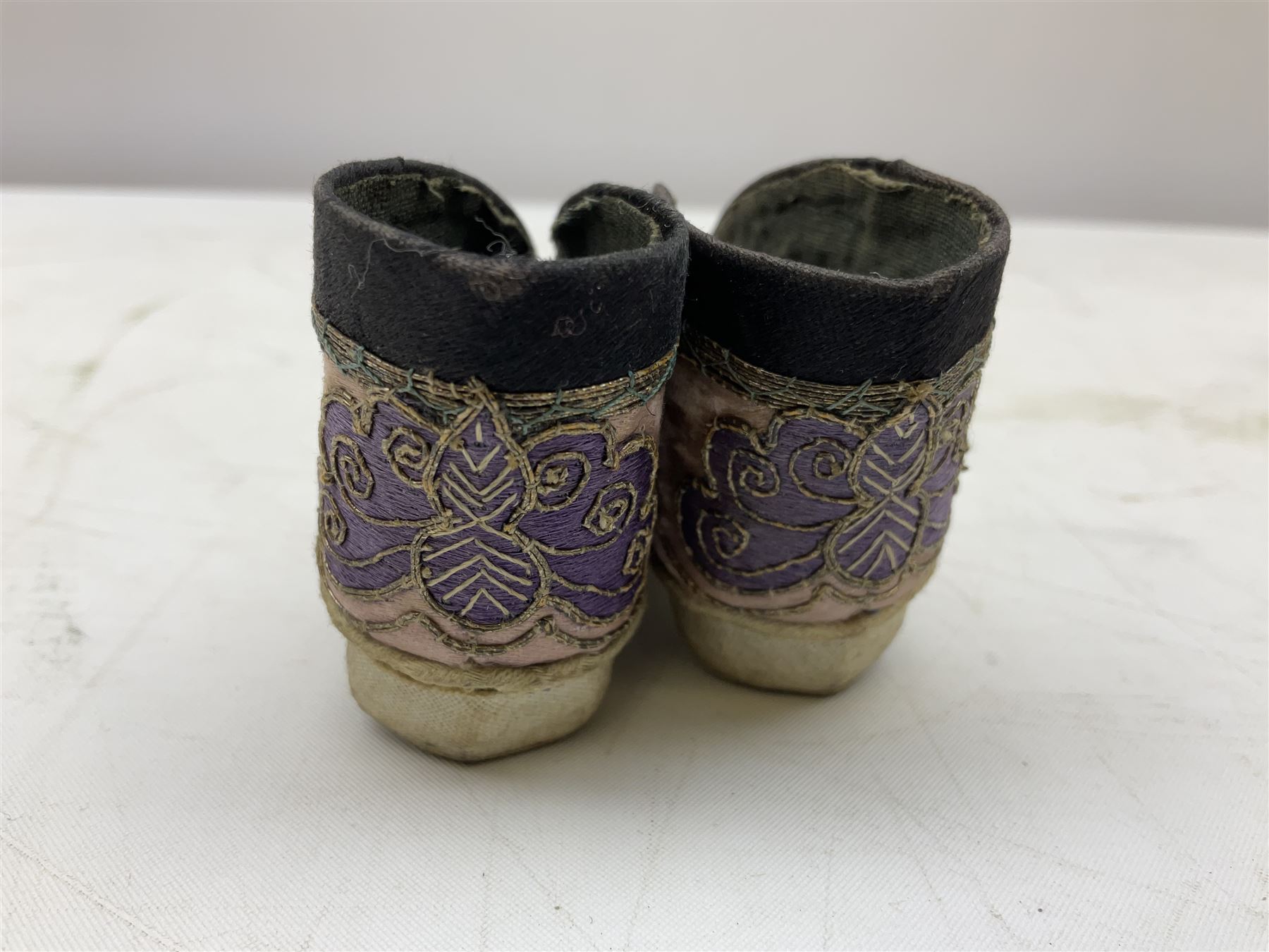 French silver plated wine taster of typical form, stamped, together with a silver plated napkin ring, and an 'Alpaca Silver' pill box with mother of pearl detailed cover, (3) together with Two pairs of late 19th/early 20th century Chinese Lotus shoes for binding feet, the first with purple silk heavily embroidered with ornate floral motifs, L10cm the second larger fuschia and black pair with thicker sole embroidered with flowers, L14cm