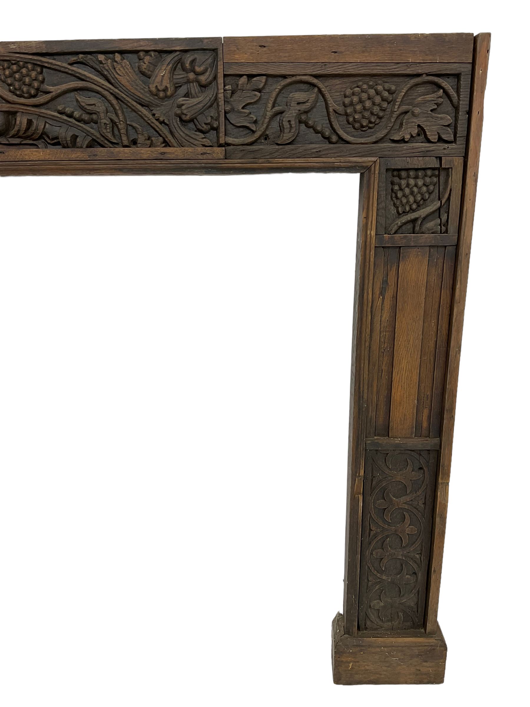 19th century Jacobean Revival oak fire surround, decorated with applied carved panels depicting foliate patterns and stylised grape vines, uprights carved with fleur-de-lis decoration