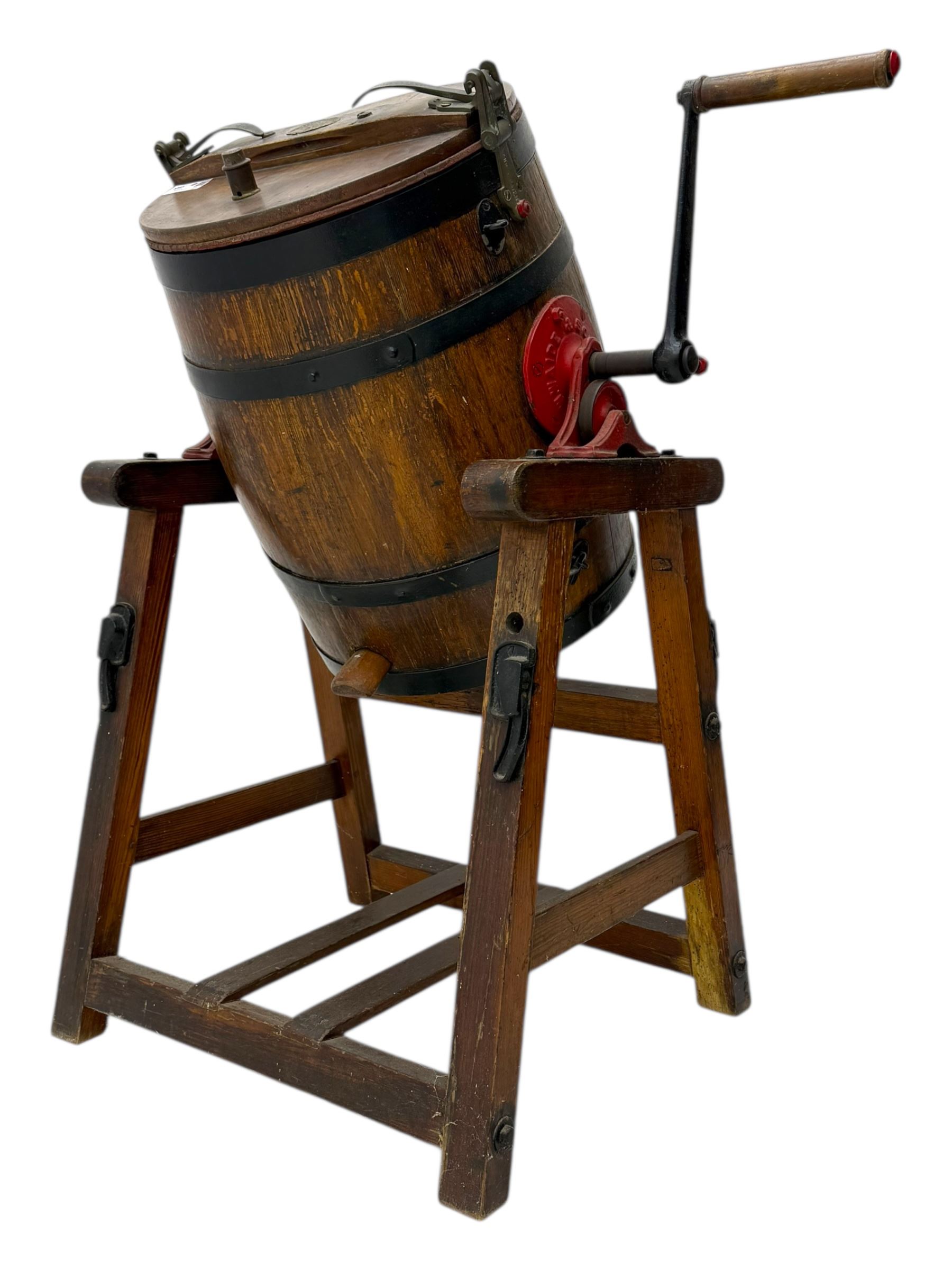 19th century oak and cast iron rotary butter churn, with coopered barrel body, domed lid with filler opening and cast iron securing arms, on tilting iron-mounted frame with crank handle and support rails