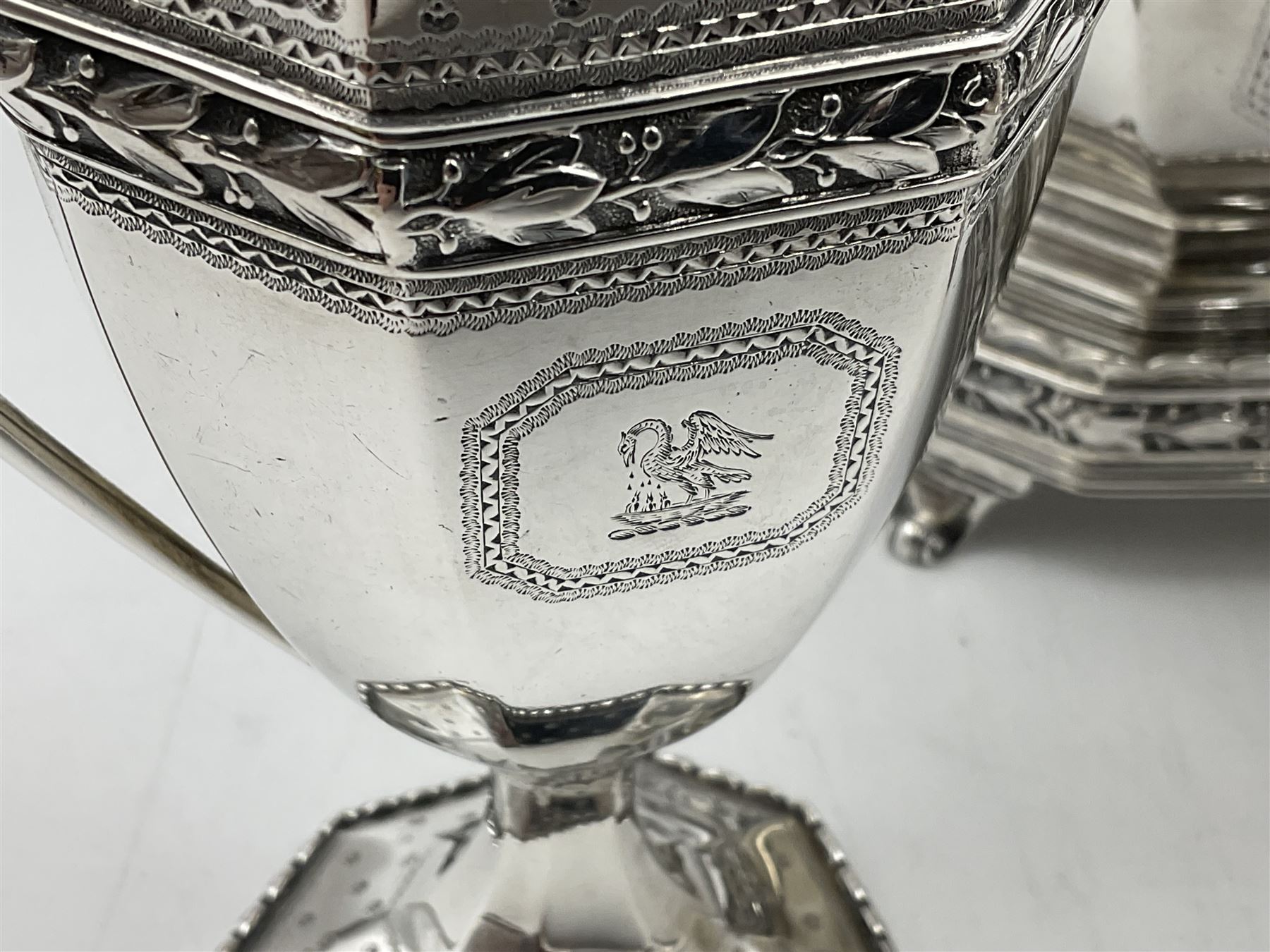 Victorian silver four piece tea service, comprising teapot, teapot stand, twin handled open sucrier and milk jug, each of octagonal form with foliate bud border and engraved decoration including crest to canted panels, and vacant panels, the teapot with ivory finial to the hinged cover and later wooden handle, hallmarked Edward Barnard & Sons Ltd, London1896, teapot including finial H15cm, milk jug including handle H16cm, teapot stand W11.5cm

This item has been registered for sale under Section 10 of the APHA Ivory Act