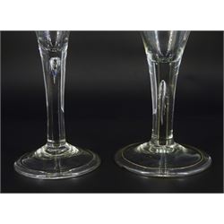 Two 18th century drinking glasses, the drawn trumpet bowls upon stems with internal tears, one elongated, and folded conical feet, largest H18cm