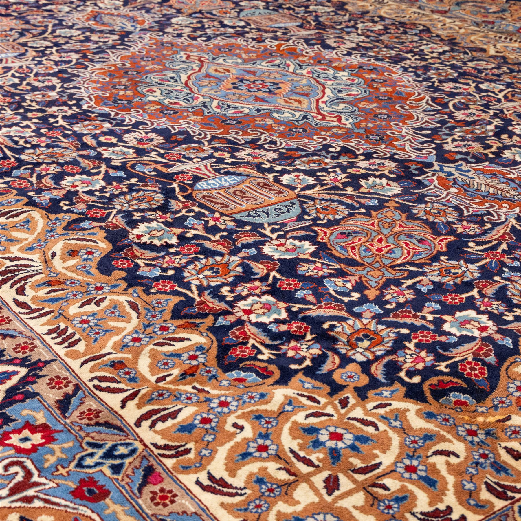 North East Persian Meshed hand-knotted carpet, deep navy field with central complex medallion and densely decorated scrolling floral sprays and palmettes, incorporating cartouche motifs enclosed by a broad tan and dark blue border ornamented by stylized vases flanked by multiple guard stripes, signed 'Amal-e Haji translates as the Work of Haji', with cotton fringe ends 