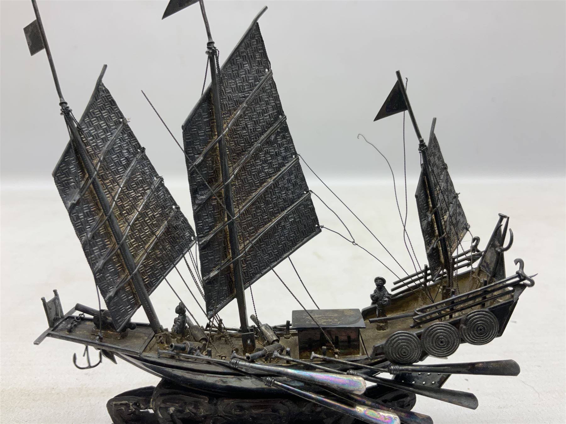 Chinese miniature silver model of a junk ship, with textured sails, mounted upon a carved wooden stand, H14cm