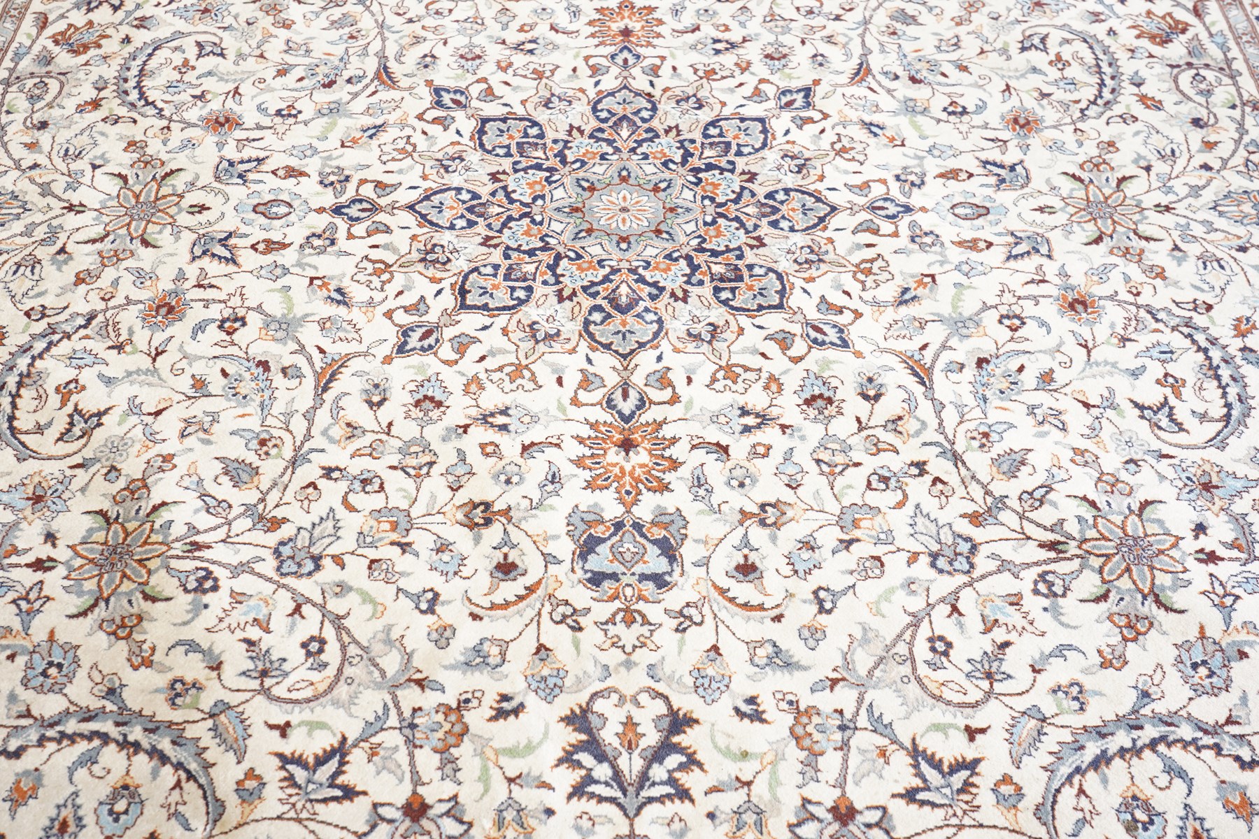 Persian ivory ground Kashan carpet, the busy field decorated with a central floral pole medallion with matching spandrels, the field profusely decorated with scrolling foliate motifs, the crimson guard stripe with repeating scrolling palmettes