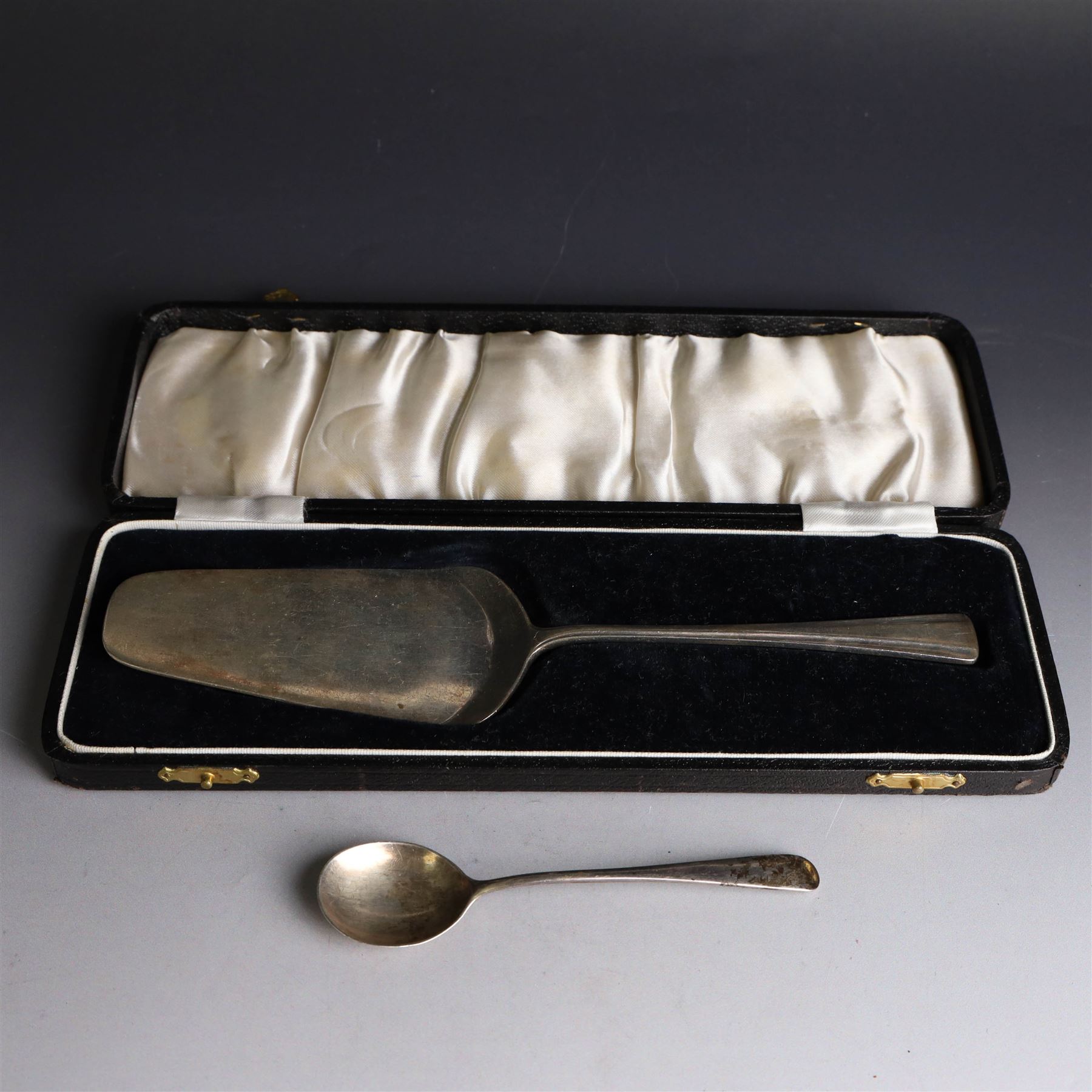 1930s silver cake slice, hallmarked Joseph Gloster Ltd, Birmingham 1934, contained within a fitted case, together with a small 1920s silver teaspoon, hallmarked John Grinsell & Sons, Birmingham 1924 