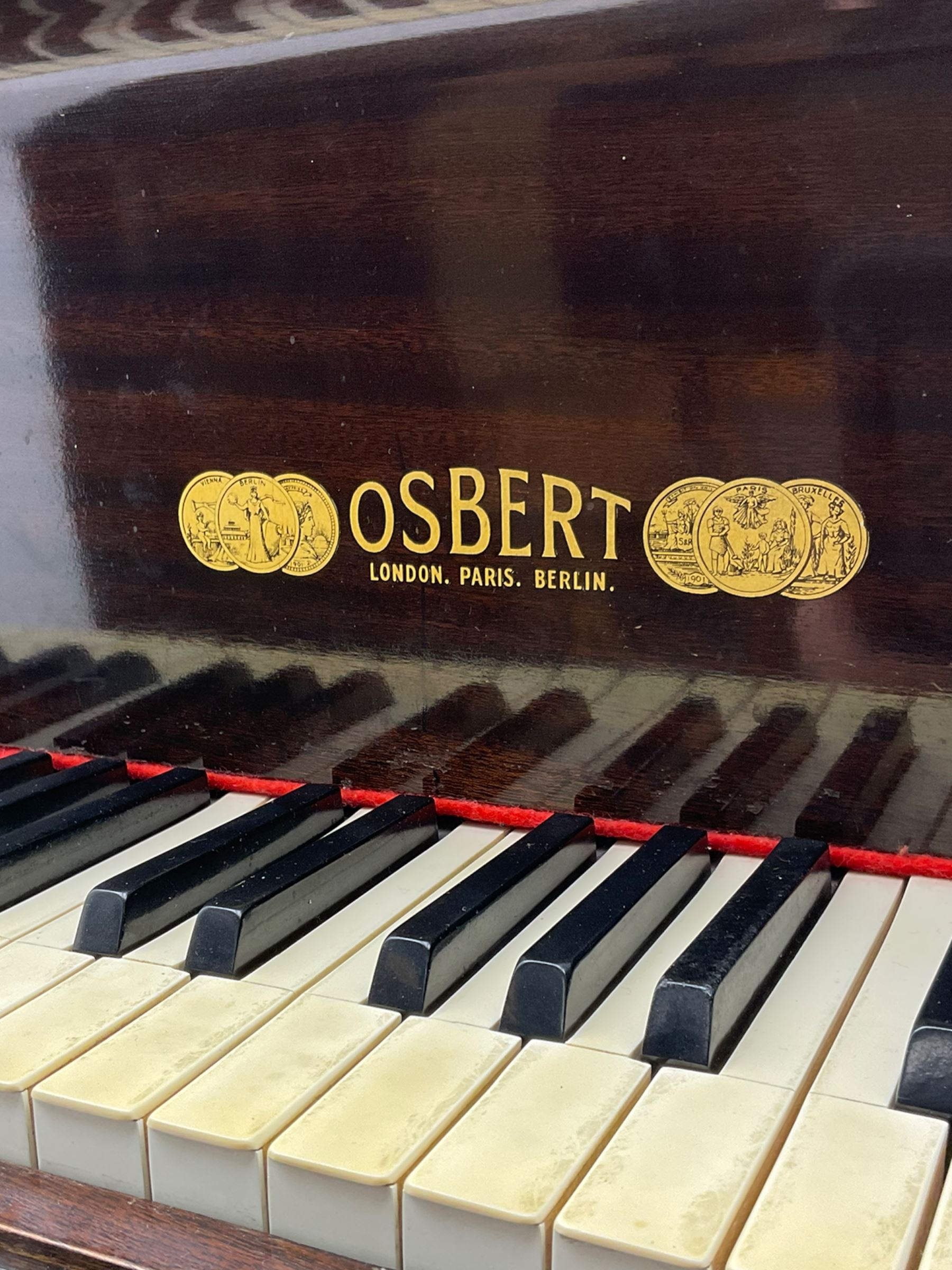 A mid 20th century English baby grand piano by Osbert, with an iron frame and overstrung stringing in a mahogany case,  conforming Lyre with sustain and una corda pedals and music desk, with original stringing, hammer action, dampers and felts, 7-1/4 octaves with 88 original ebony and ivory covered keys, with stool