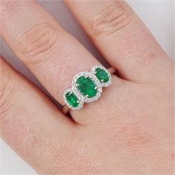 Platinum emerald and diamond trilogy ring, three oval cut emeralds surrounded by round brilliant cut diamonds, hallmarked, total emerald weight approx 1.05 carat, total diamond weight approx 0.25 carat