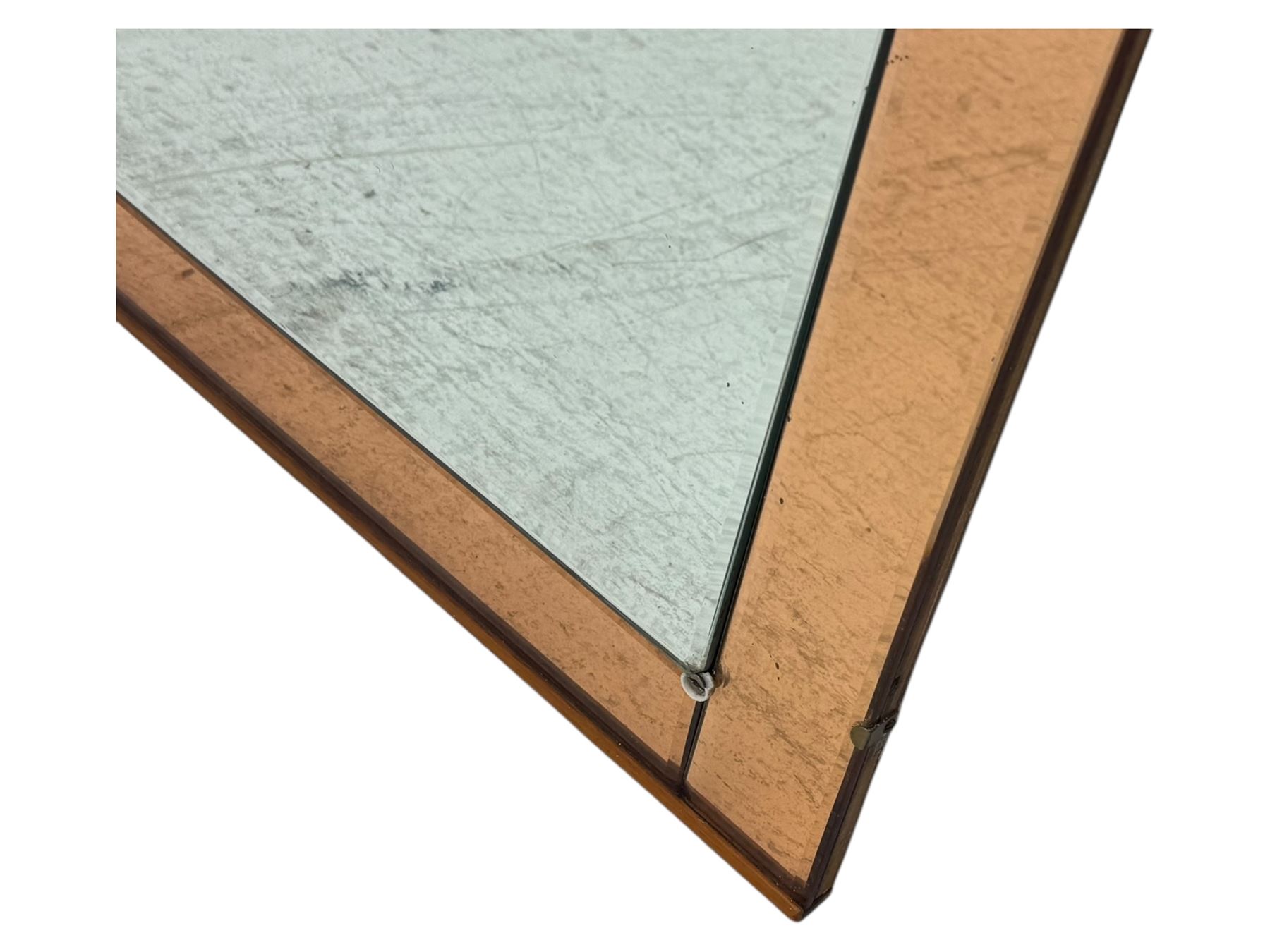 Frameless art deco mirror, scalloped copper tinted border central fan motif, bevelled edges with decorative screw caps