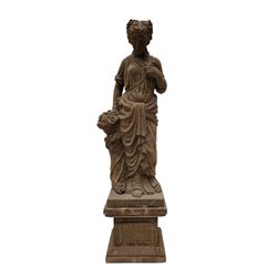 Hand carved stone Neoclassical figure of the Roman goddess Flora, her hair pinned with roses, draped in a toga, holding a basket of flowers in her right hand, raised on a stepped square plinth base 