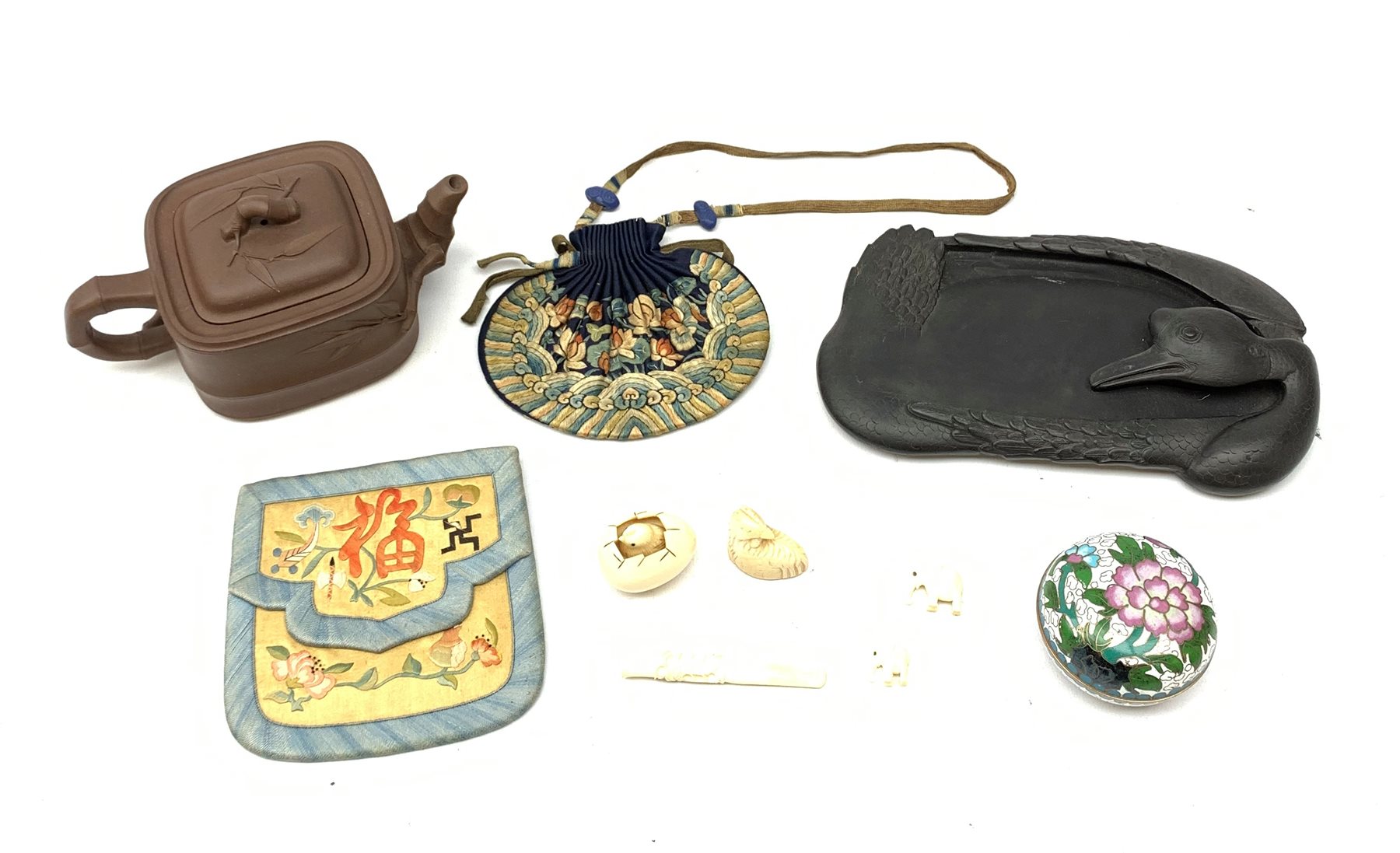 A Japanese ivory netsky modelled as a chick hatching from an egg, with marks beneath, together with a further netsky modelled as a seated chicken, also marked, a carved ivory cheroot holder, and two small carved ivory elephants, plus a Japanese stand modelled in the form of a crane, with character marks to base, a Japanese bamboo detailed teapot, cloisonne circular  pot, and an embroidered pouch and purse. 