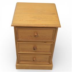 Pair of late 20th century waxed pine bedside chests, three drawers with moulded edges and turned pulls, raised on a plinth base 