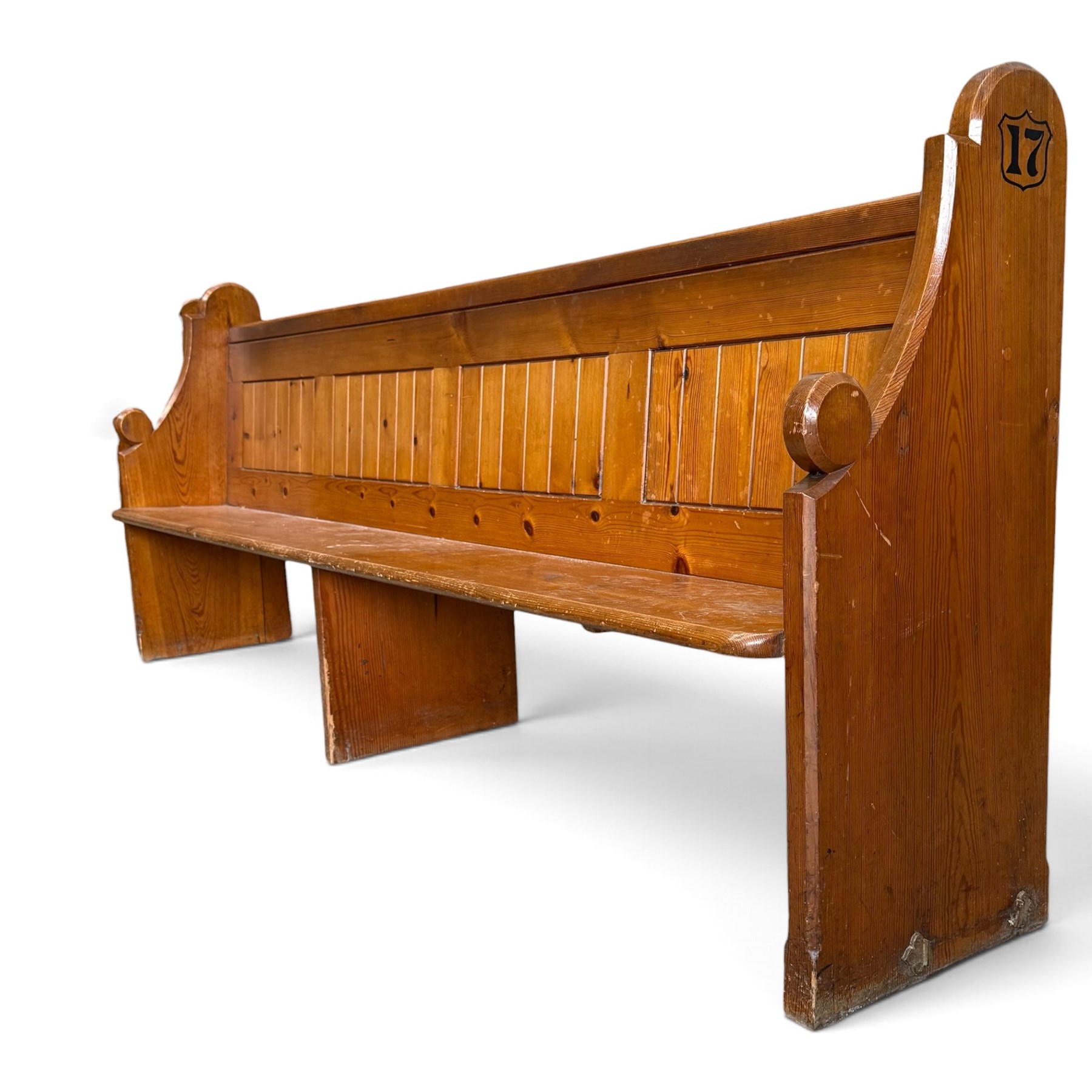 Early 20th century stained pine ecclesiastical church pew, the shaped end supports flanking slatted and panelled back, with black stencilled number '17' to the side