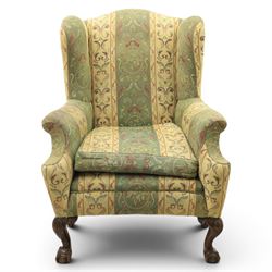 Queen Anne style wingback armchair, upholstered in green and cream foliate fabric, shaped arms on ball and claw feet