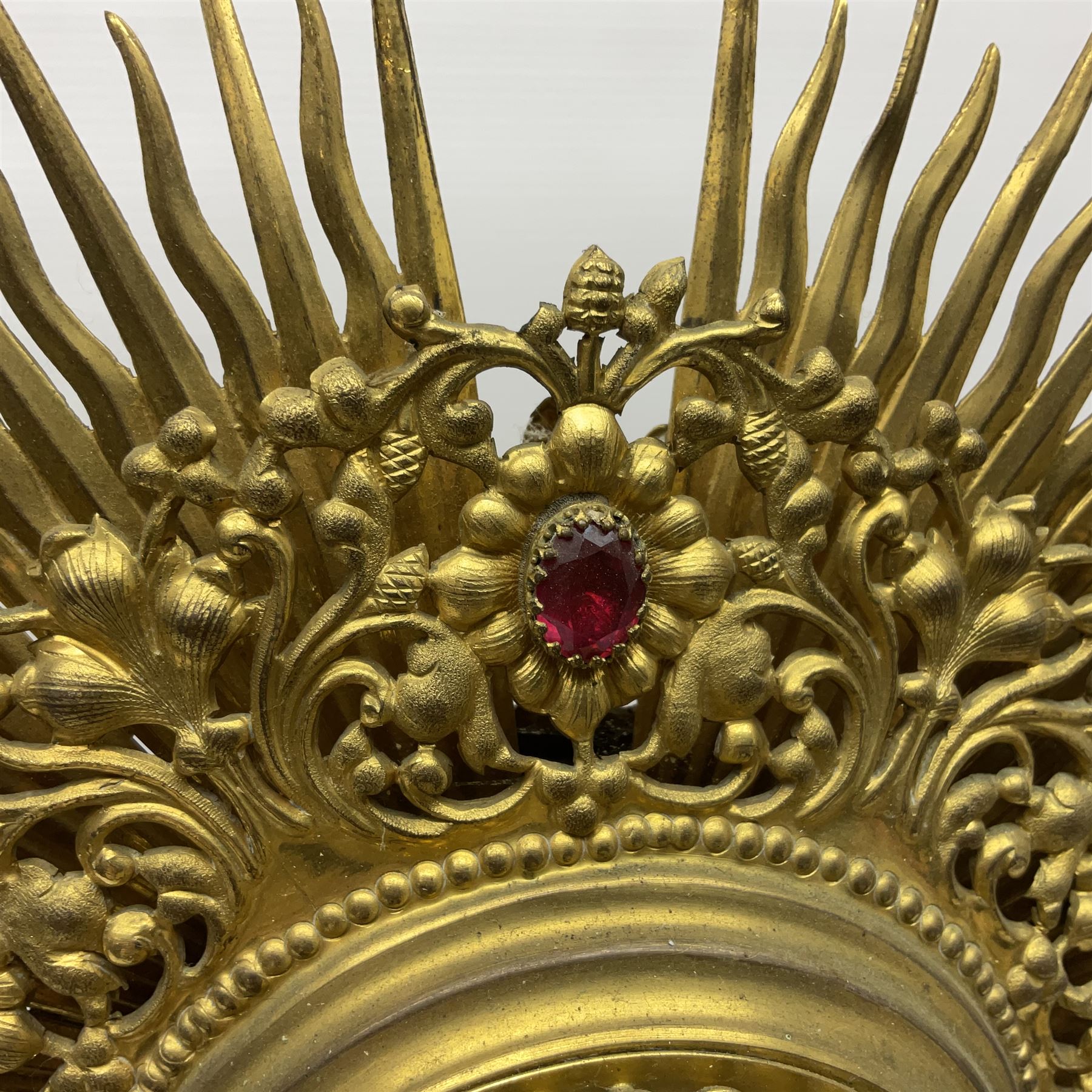 20th century gilt metal monstrance, in the Gothic revival style, with glazed aperture to centre surrounded with clear paste stones, in a pierced floral and scroll border set with coloured paste stones, within a sunburst surround, on a paste set knopped stem and similar foliate foot, H59.3cm
