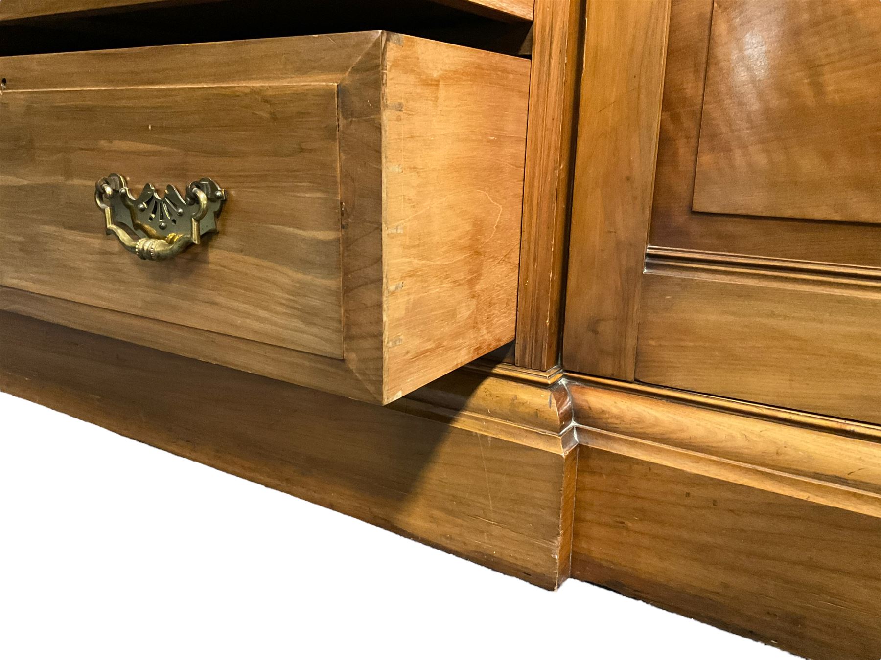 Edwardian walnut combination breakfront triple wardrobe, projecting cornice over cushioned and fluted frieze, central fielded panelled cupboard carved with foliate decoration above two short and three long drawers, flanked by two bevelled mirror doors enclosing hanging hooks with single drawers to base, retailed by J Tonks & Sons, Scarborough